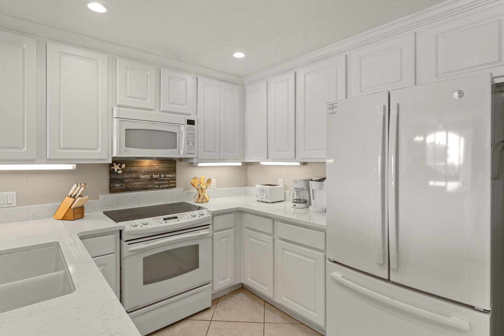 Fully equipped kitchen features white cabinets, granite countertops, and all essential appliances for preparing your favorite meals during your stay.