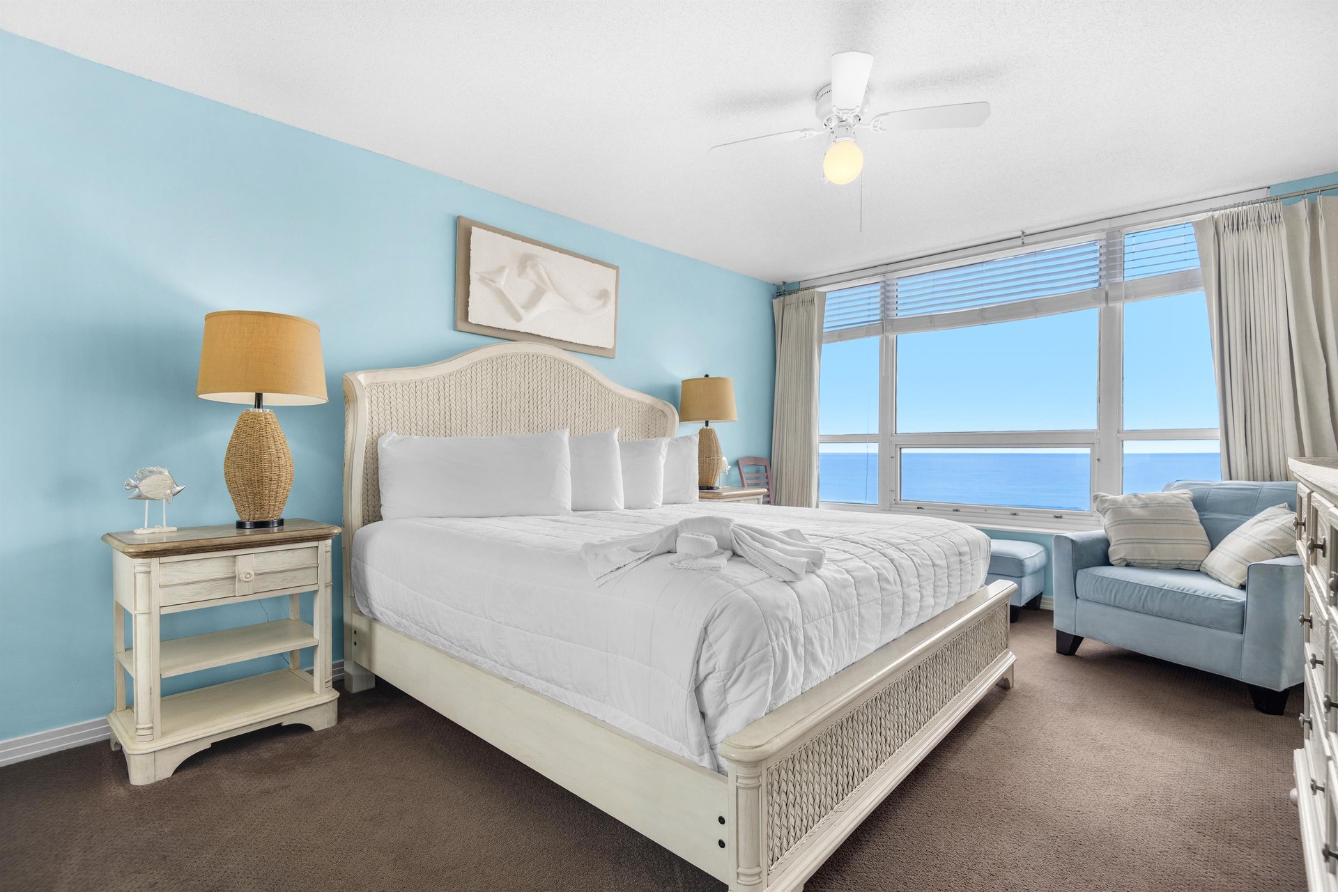 Bedrooom1 Wake up to breathtaking ocean views from your comfortable bed. Soft blue walls and coastal furnishings create a serene retreat.