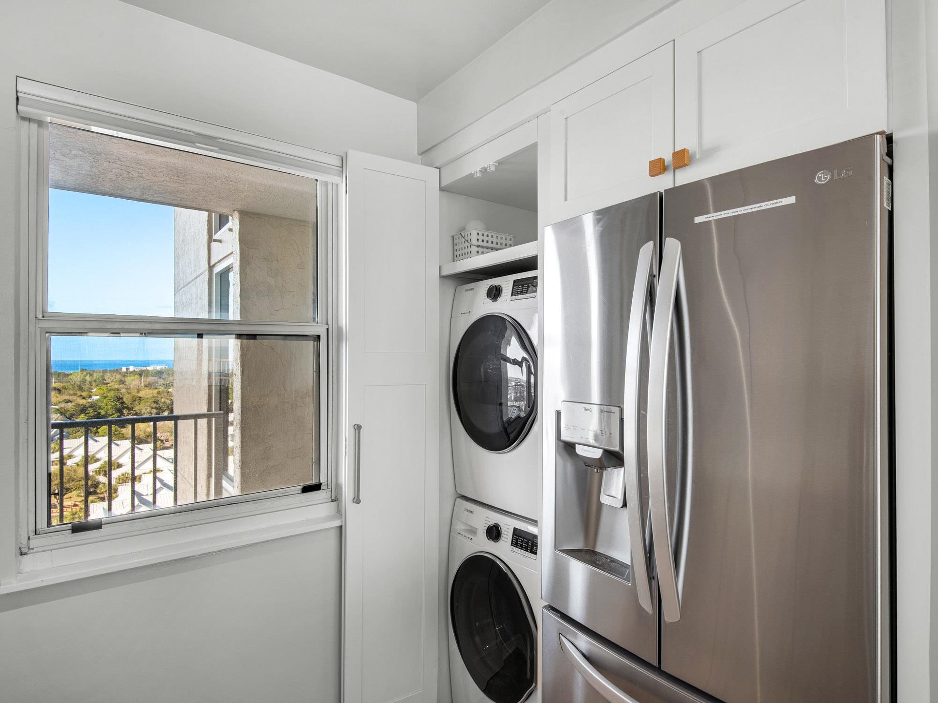 Your bright laundry nook features stacked washer and dryer with crisp white cabinetry