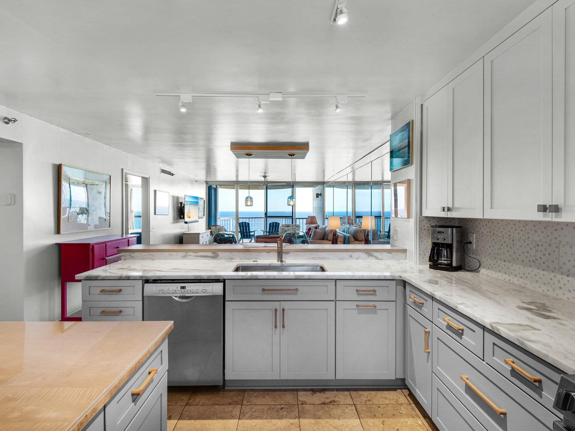 Cook with stunning ocean views in this sleek modern kitchen featuring marble countertops, stainless appliances, and panoramic windows.