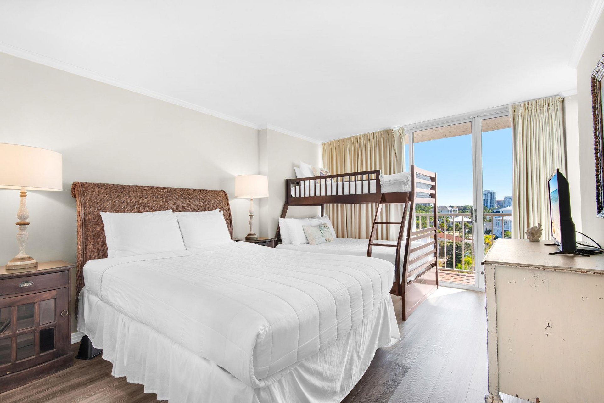 Relax in your bright bedroom featuring a cozy main bed and convenient bunk bed, with city views streaming through large windows.