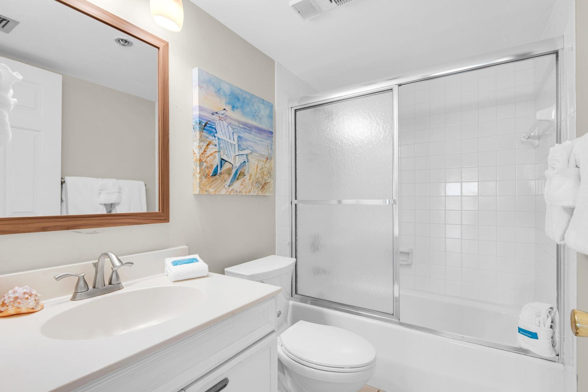 Step into your pristine bathroom with sparkling white fixtures and a spacious glassenclosed shower perfect for refreshing after beach days.