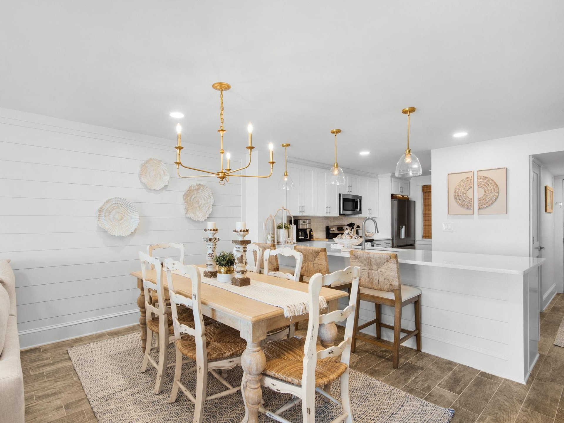 Your elegant dining space flows into a bright kitchen with brass fixtures and coastal charm—perfect for memorable meals together.