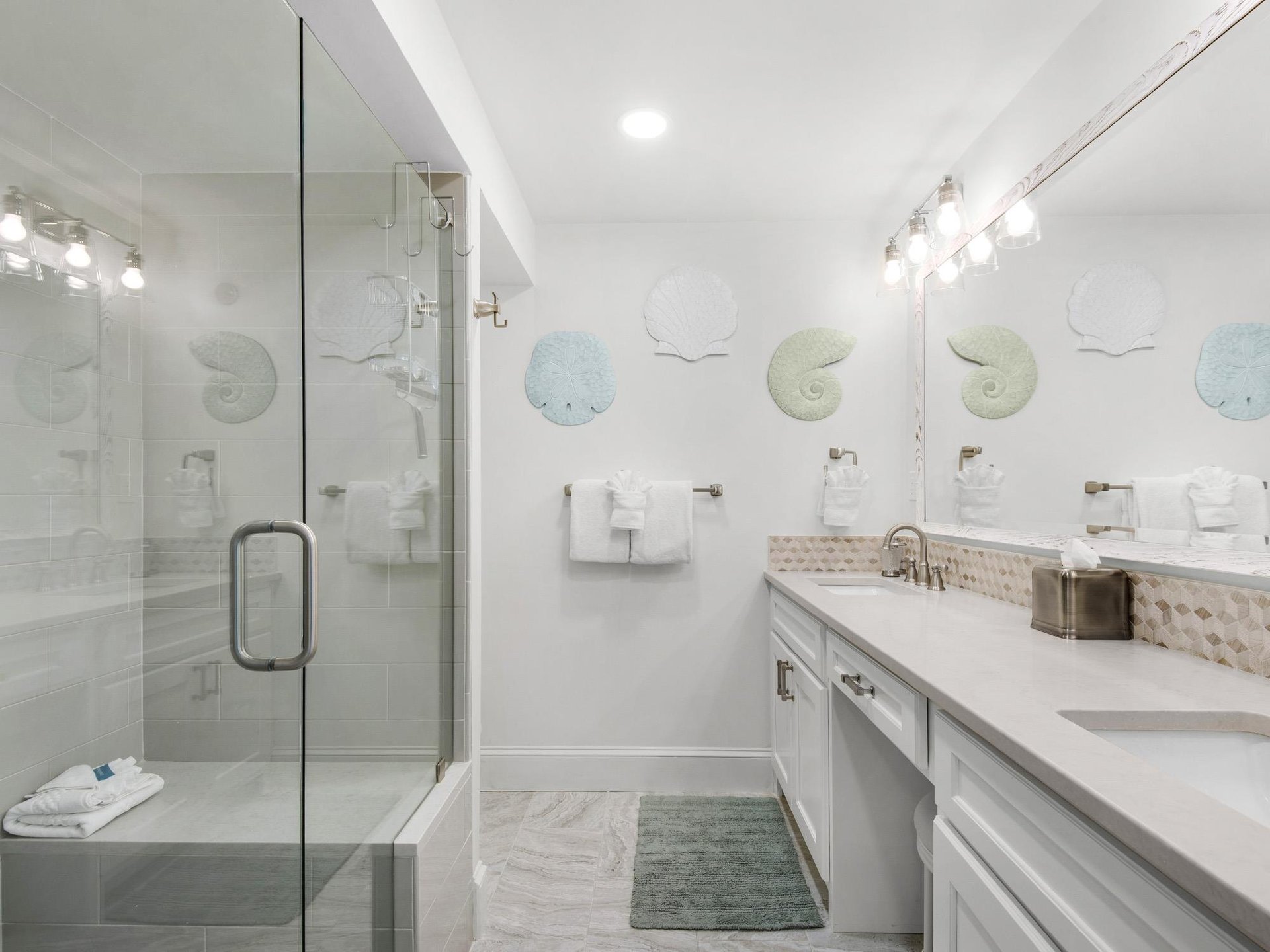 Bathroom 1  Unwind in your coastalinspired bathroom with glassenclosed shower, elegant dual vanity, and charming seathemed touches.