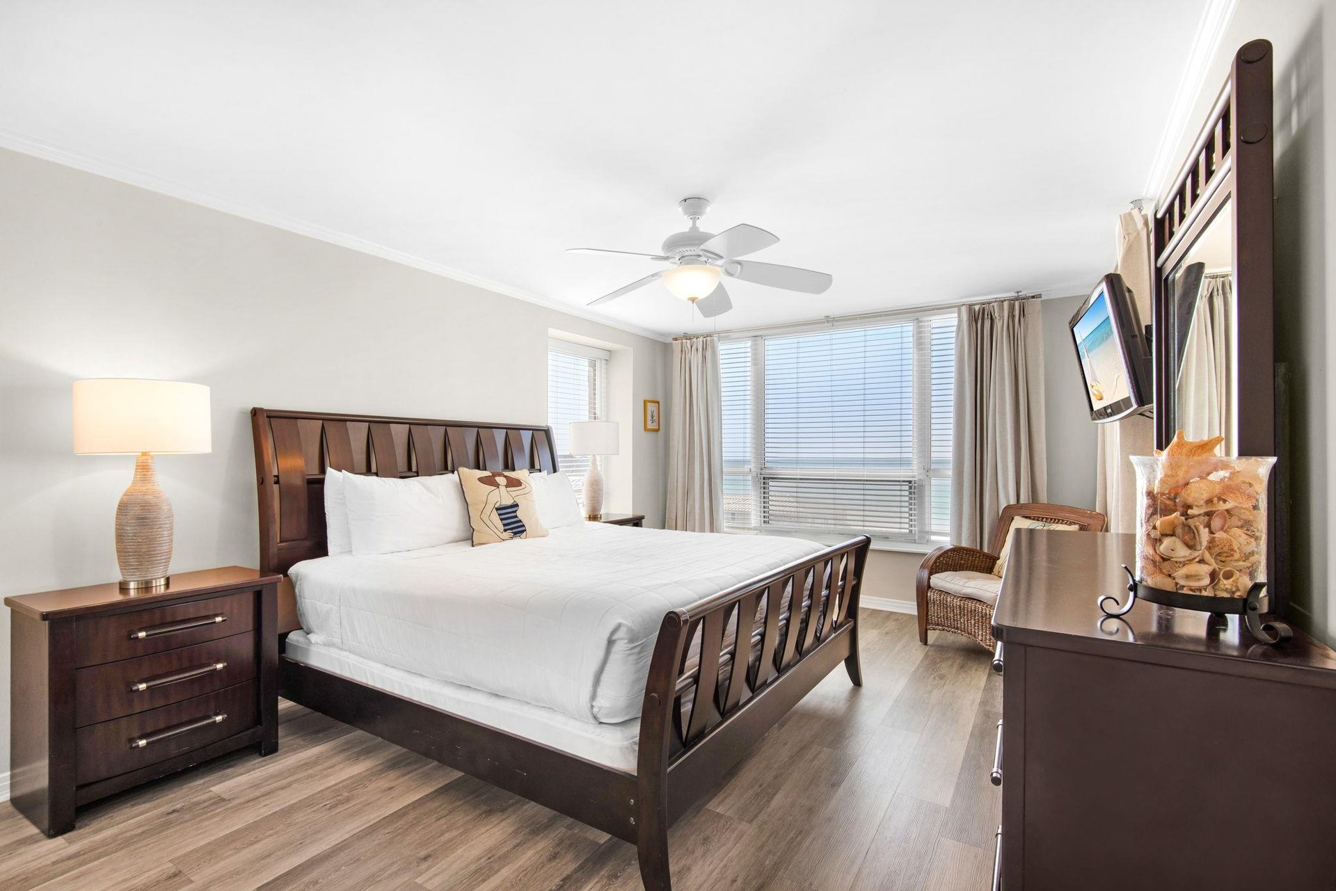 Unwind in your elegant bedroom featuring rich wood furnishings, crisp linens, and gentle natural light streaming through large windows.