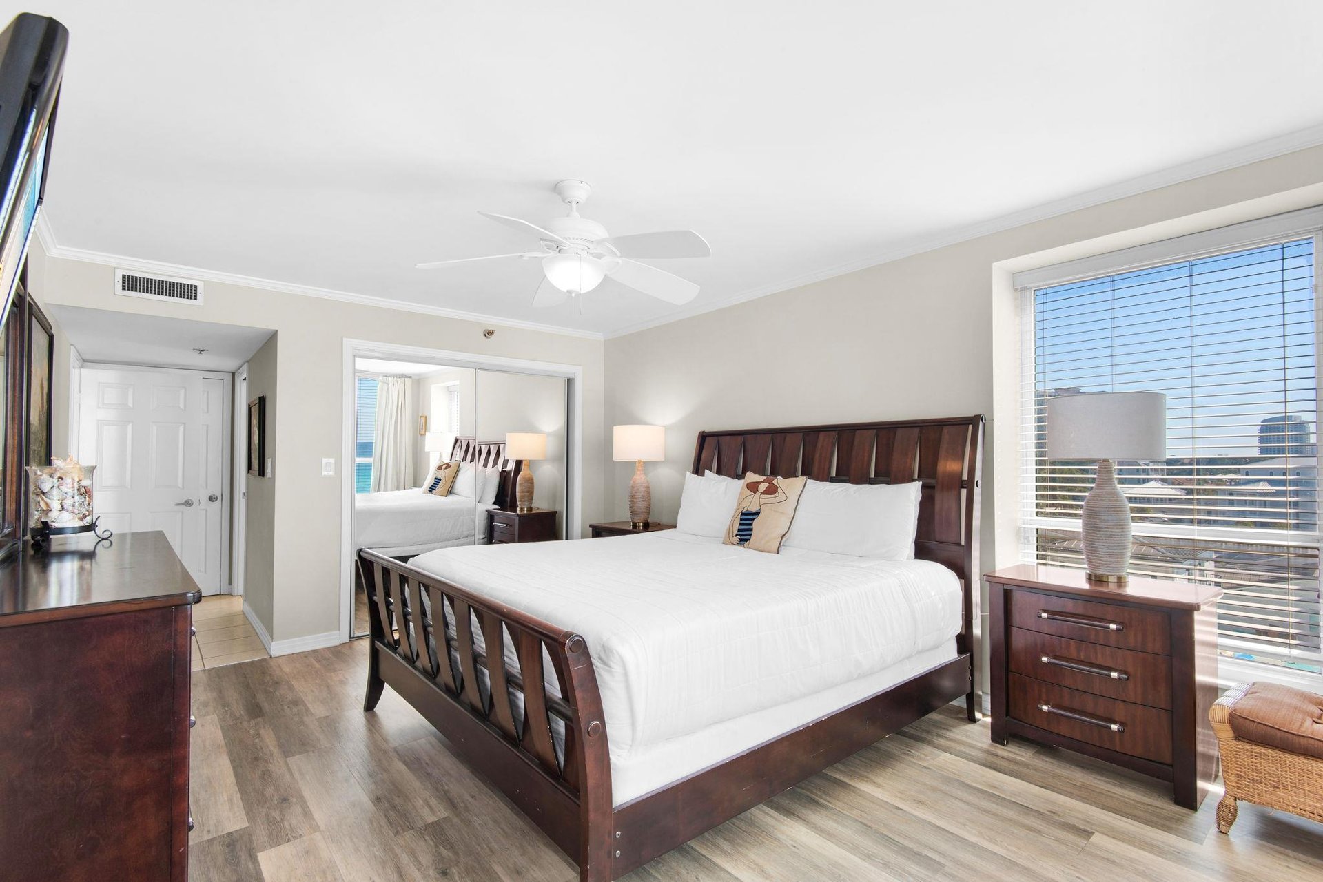 Sink into crisp linens and rich wood furnishings in bedroom 1, where city views and gentle ceiling fan breezes create the perfect retreat.