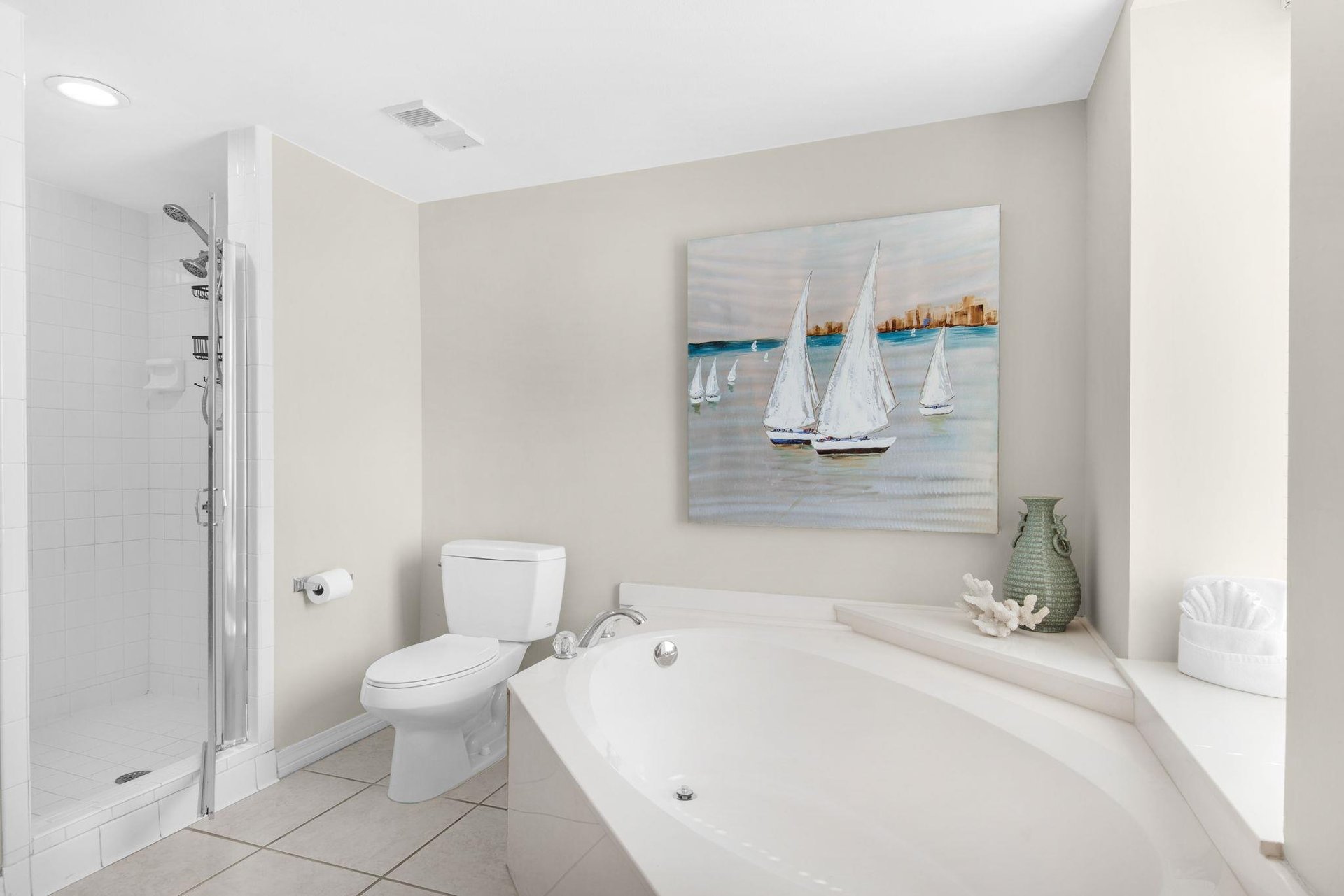 Unwind in your spalike bathroom with a soaking tub and separate glass shower, complete with coastal artwork for a serene retreat.