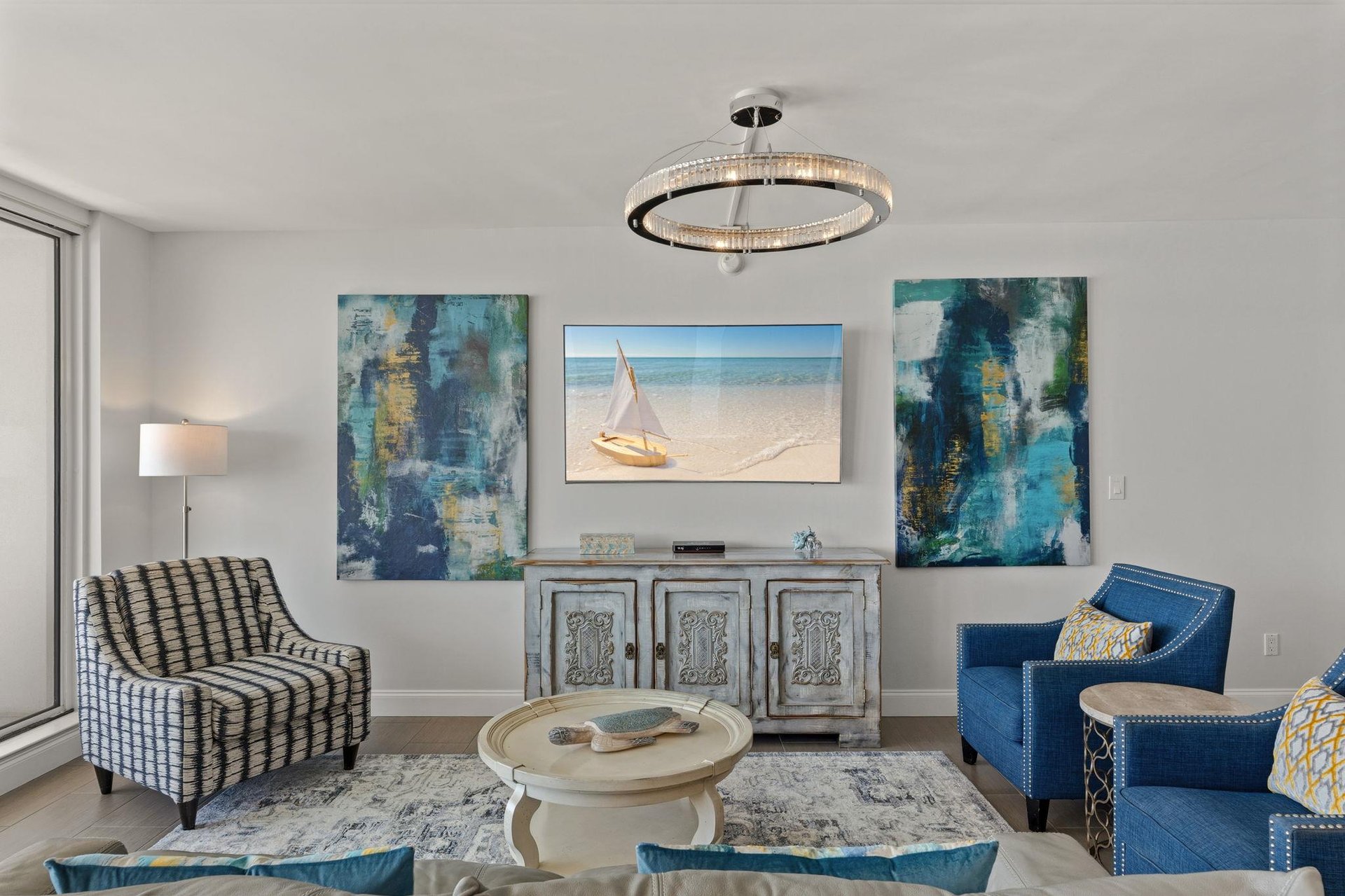 Relax in your stylish living space with coastal artwork, plush seating, and elegant lighting creating the perfect atmosphere for unwinding.