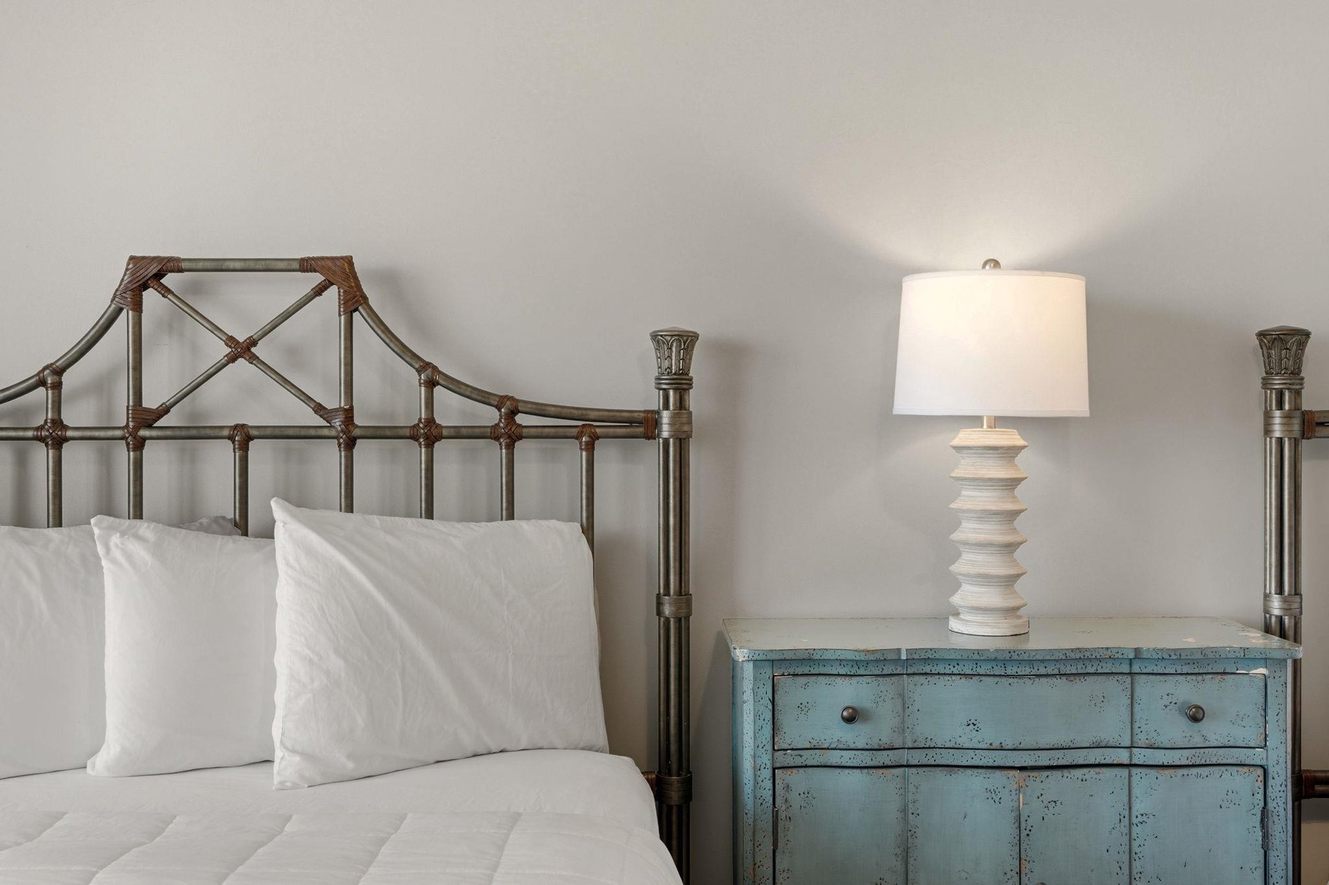Relax in your elegantly appointed bedroom with a charming vintage metal bed frame and rustic blue nightstand, softly lit for comfort.
