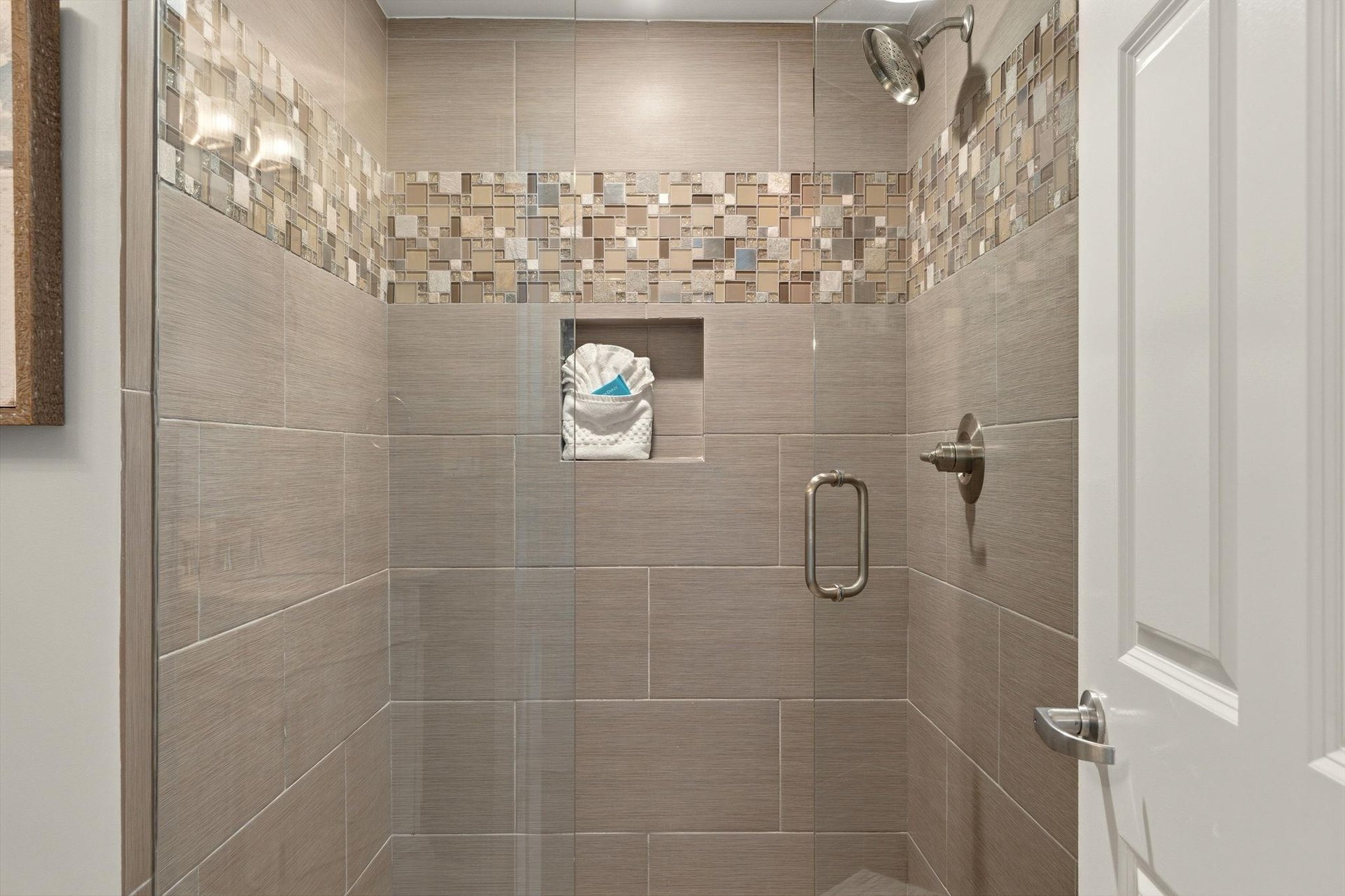 Step into your elegant tiled shower with beautiful mosaic accents and a convenient builtin niche for your toiletries.