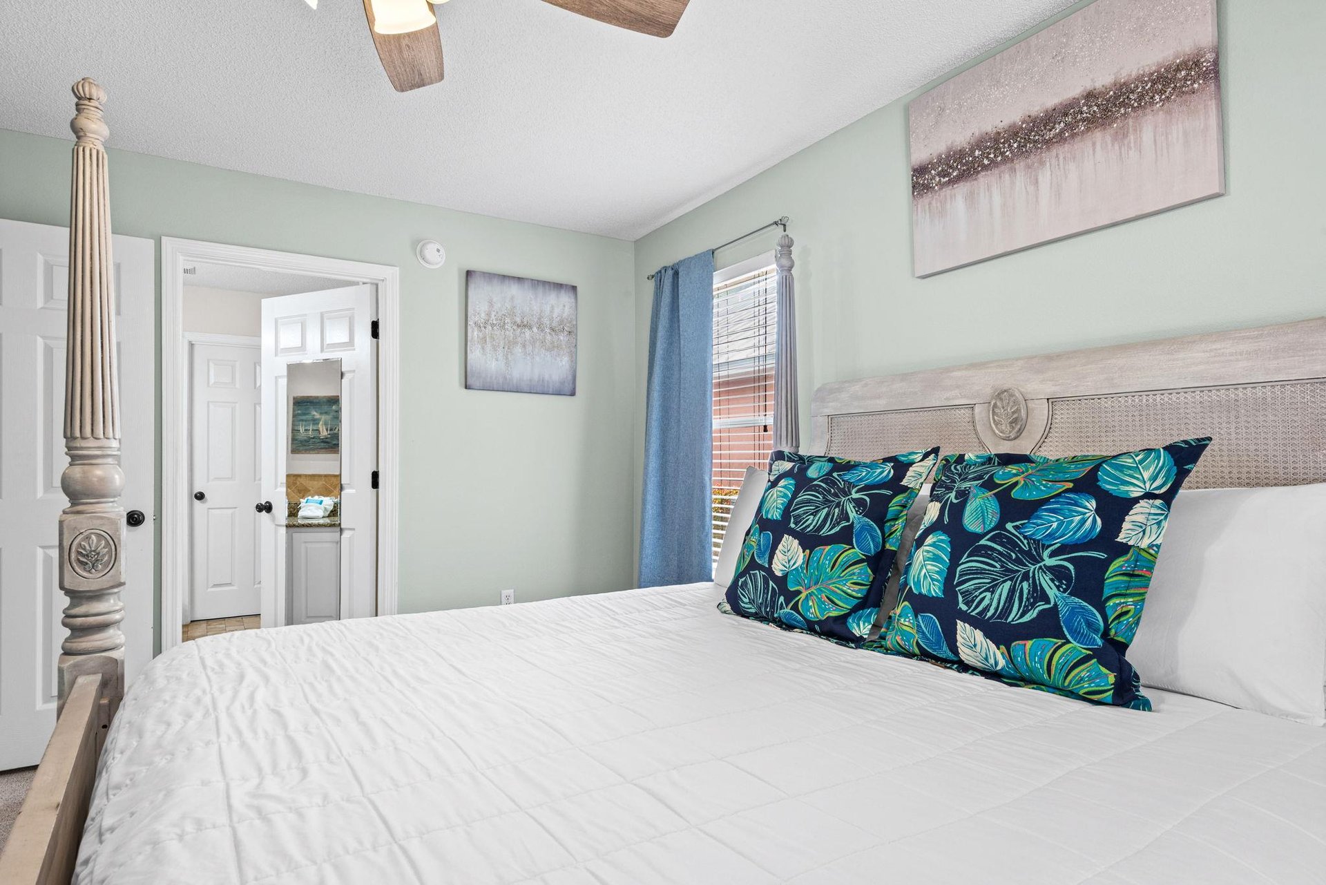 Sink into this serene bedrooms plush bedding where soft mint walls and natural light create your perfect retreat.