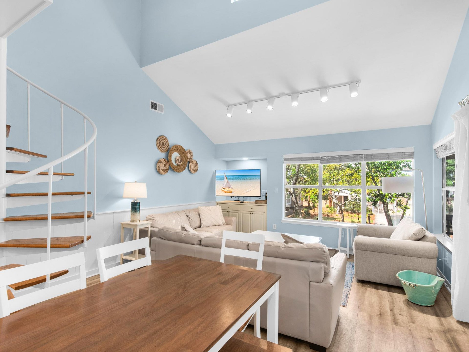 Relax in your bright living room with cozy seating, entertainment center, and beautiful garden views through large windows.