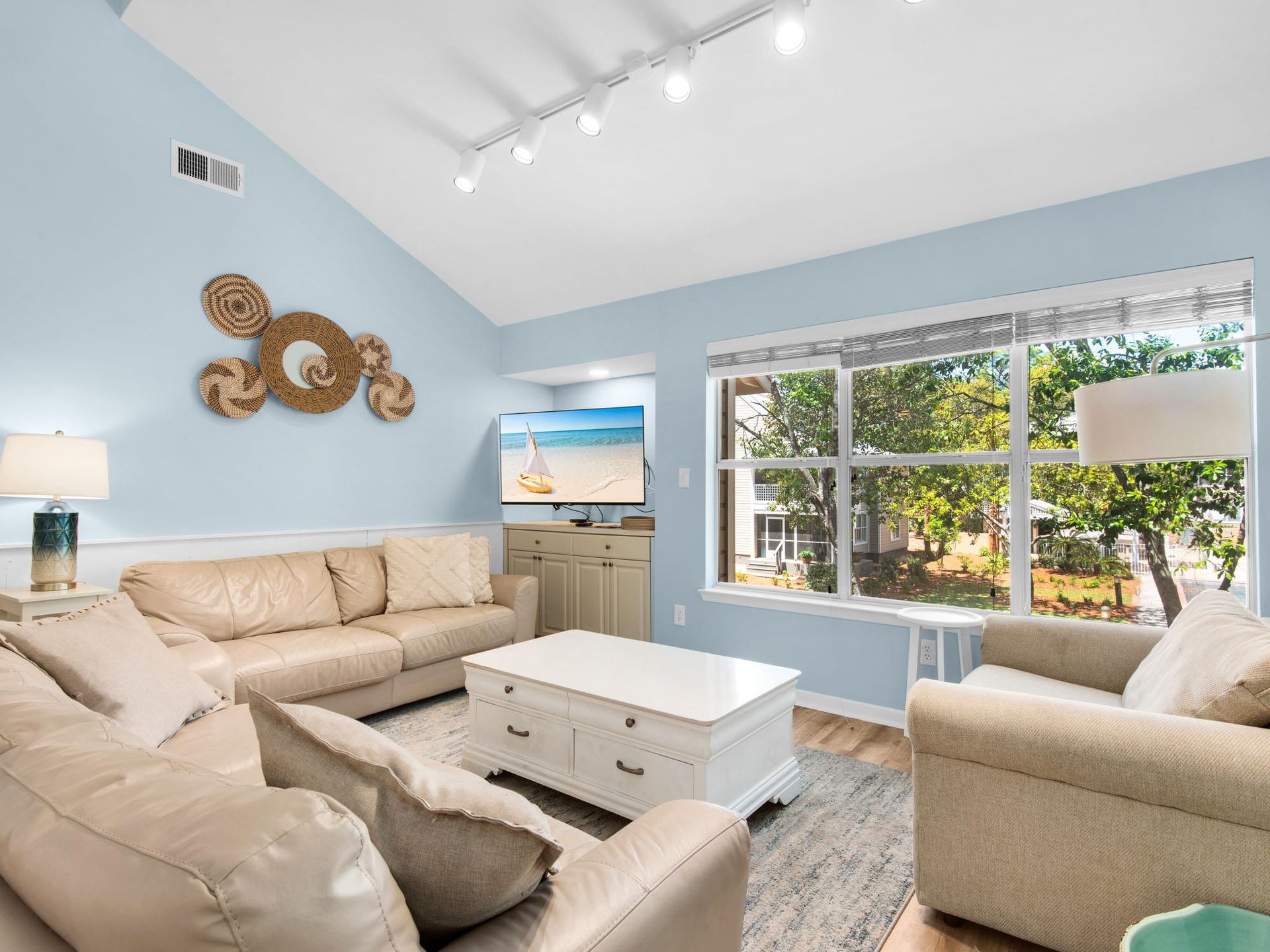 Unwind in your bright living room with vaulted ceilings, comfortable seating, and peaceful garden views through oversized windows.