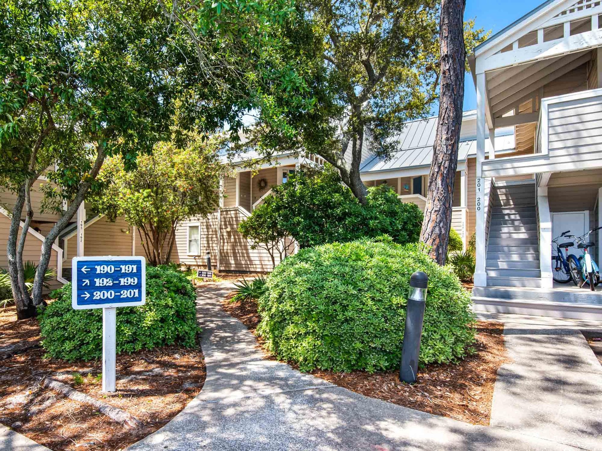 Charming vacation rental buildings nestled among mature trees with clear directional signage for easy navigation.