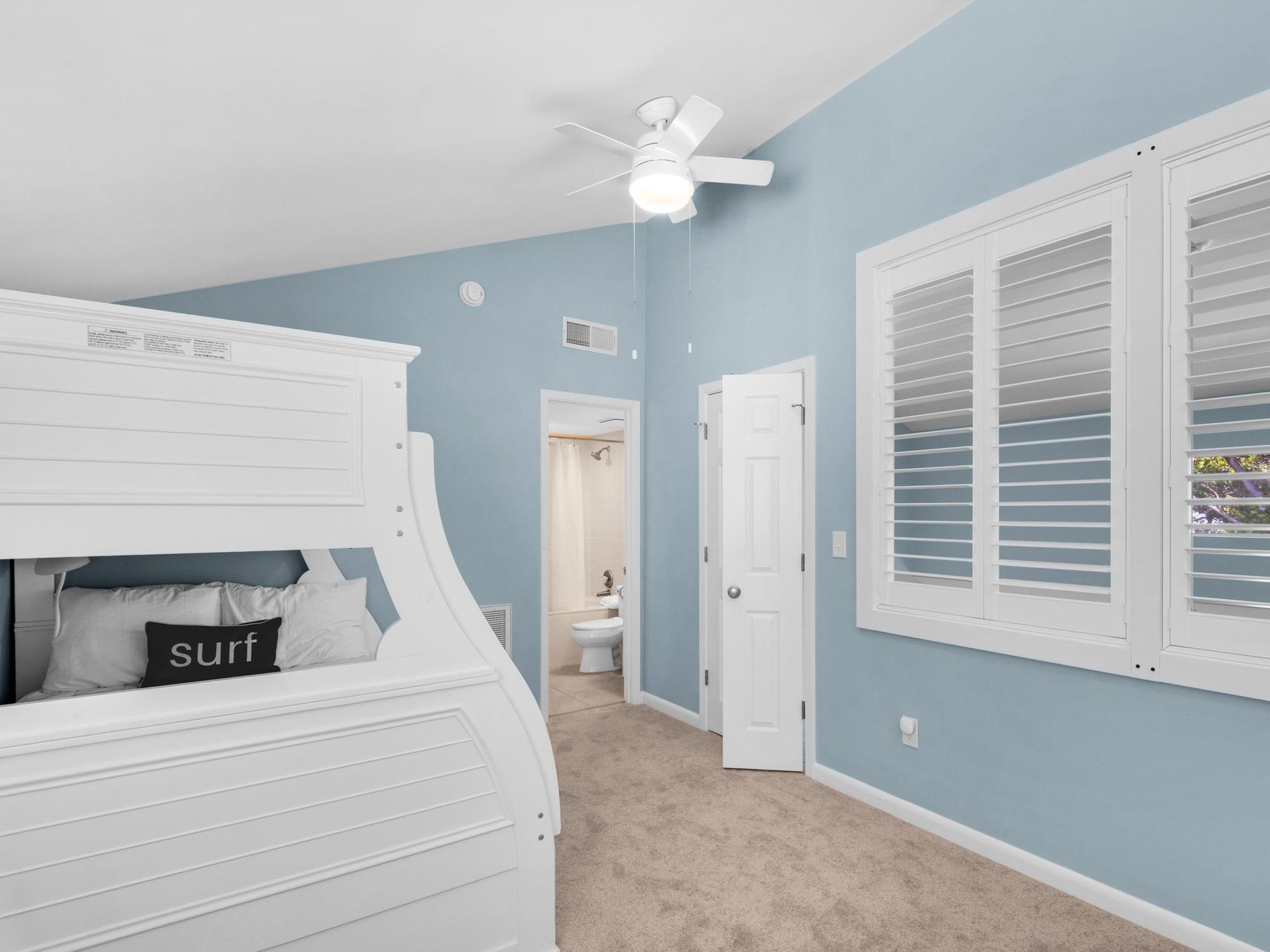 Drift off to sleep in your serene coastal loft bedroom with bunk beds, private bathroom access, and soothing blue walls.