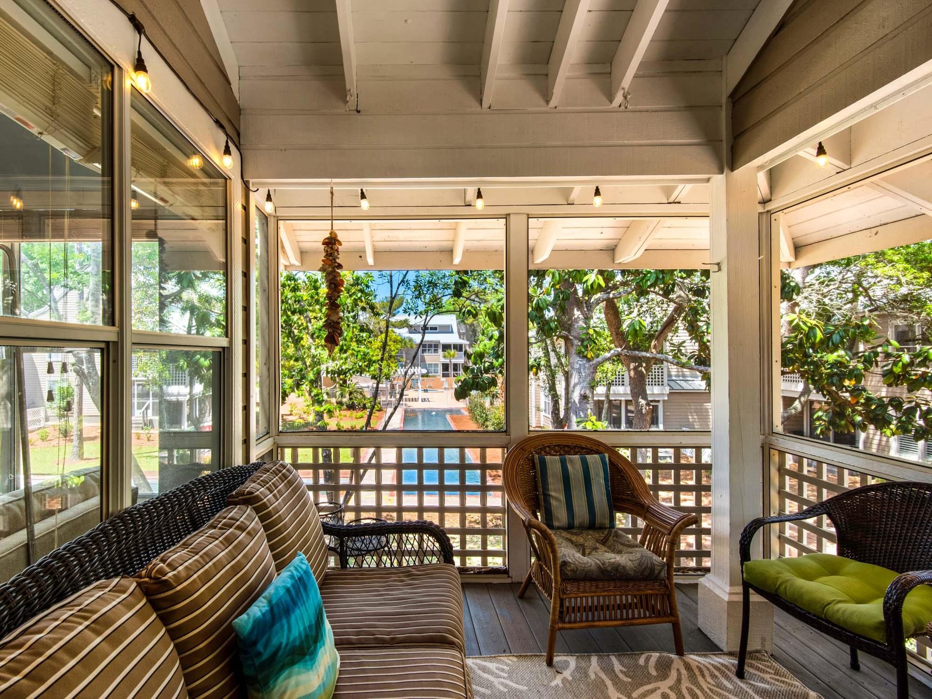 Relax on your screened porch with comfortable wicker seating and string lights, overlooking the fountains through lush tropical views.