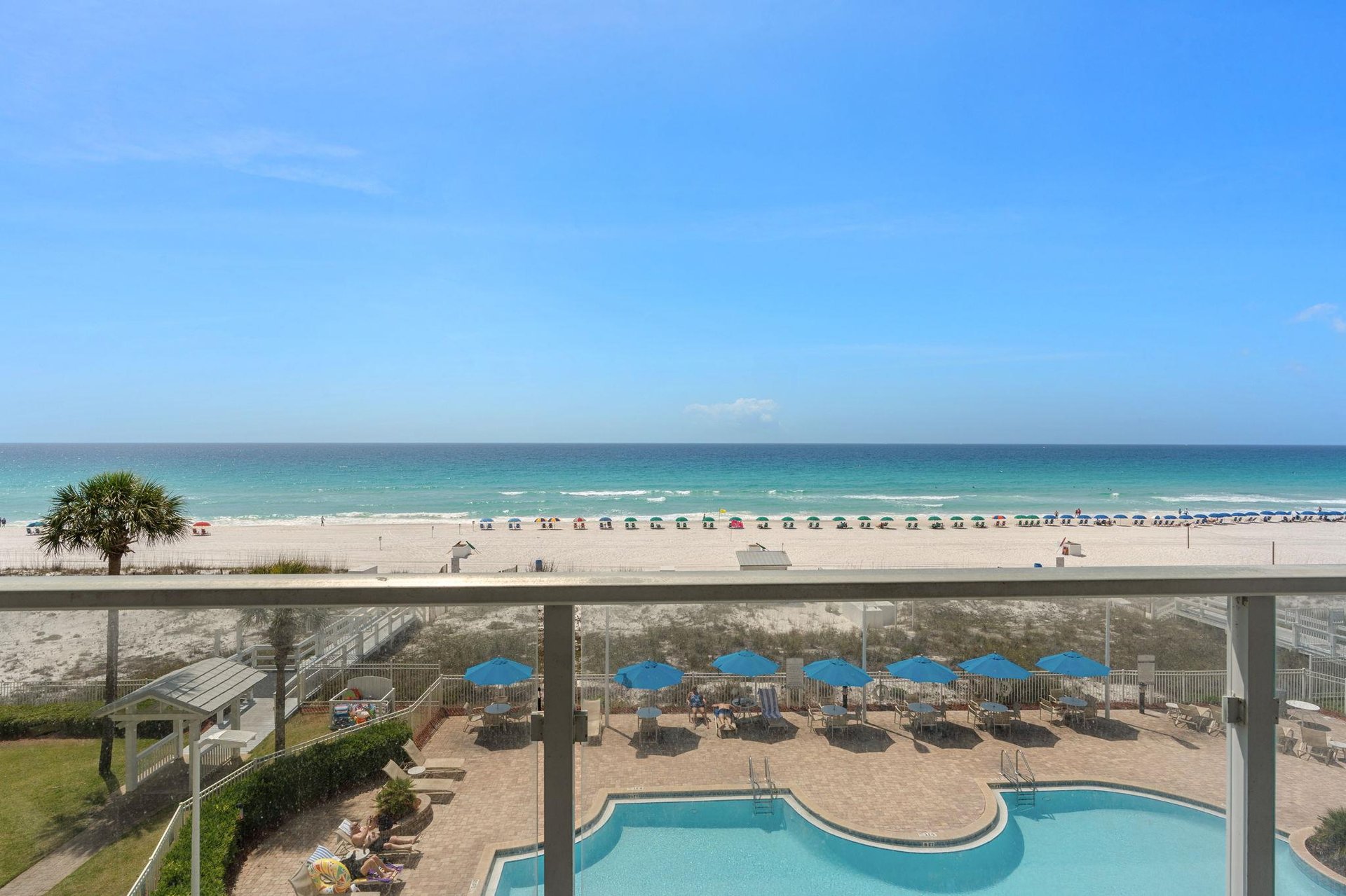 Stunning beachfront view with pristine white sand, turquoise waters, and resort pool deck area.