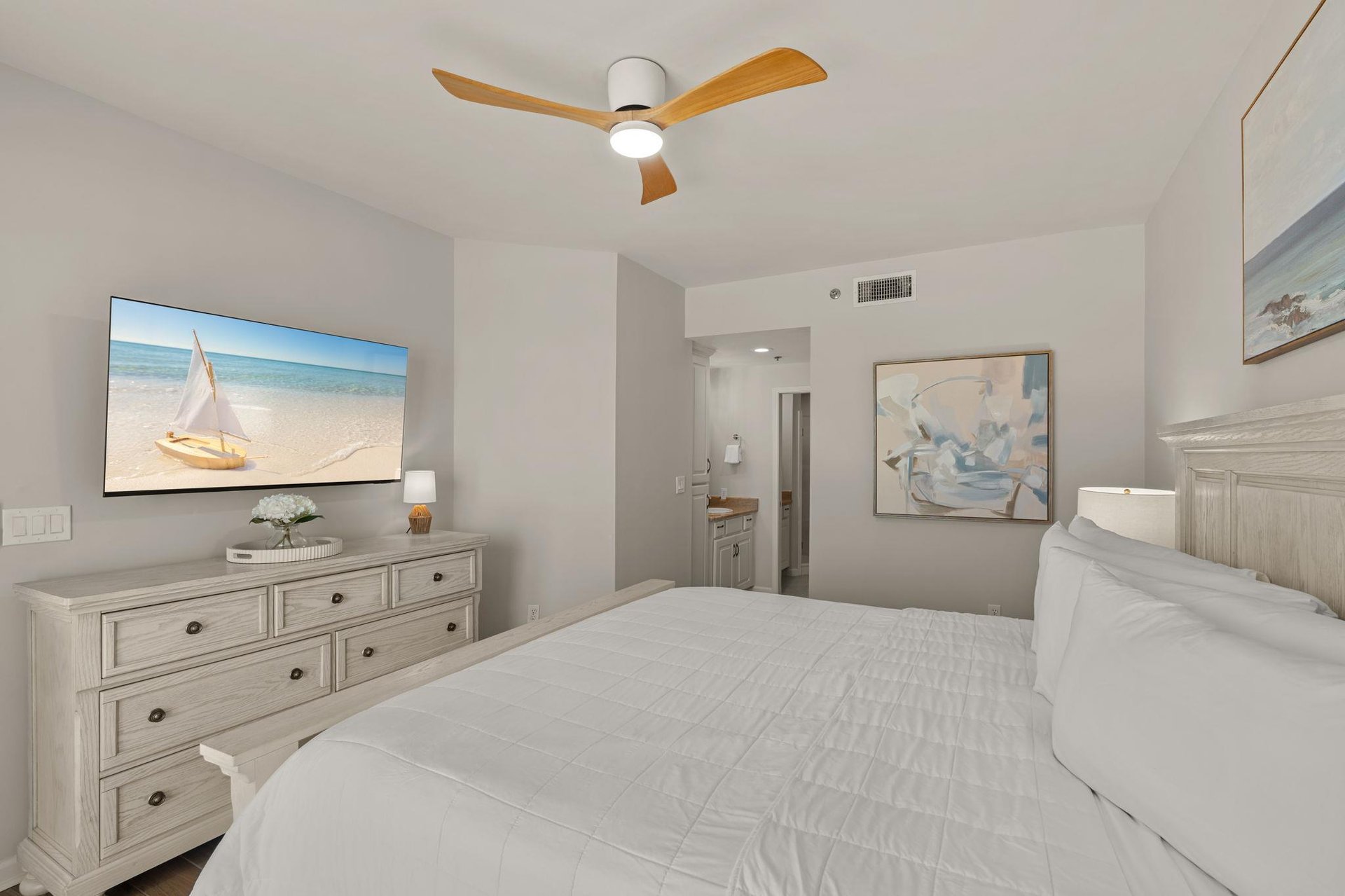 Bedroom 1 where crisp white linens and gentle sea breeze artwork create your perfect retreat.