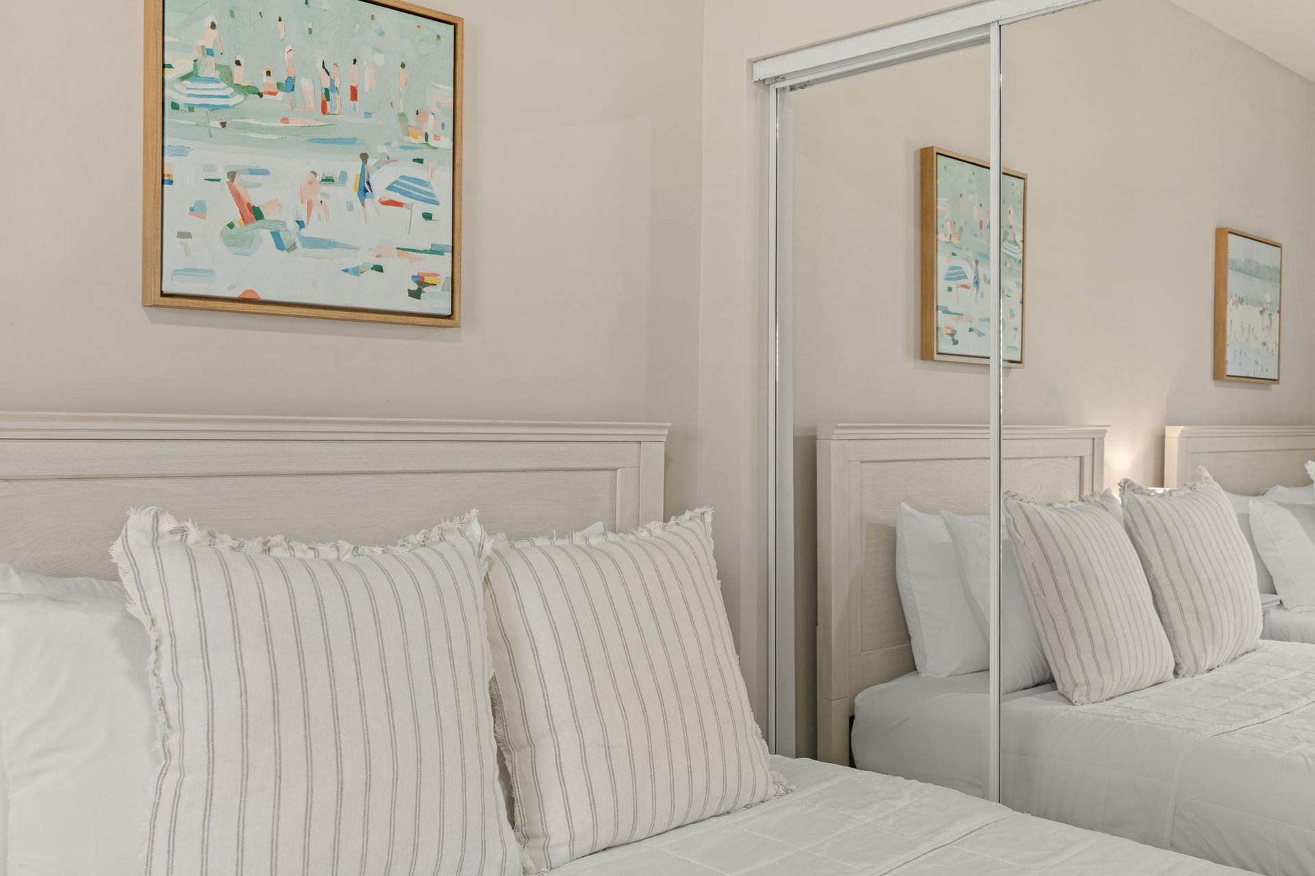 Sink into crisp white linens in your serene bedroom, where coastal artwork adds gentle splashes of color to your peaceful retreat.