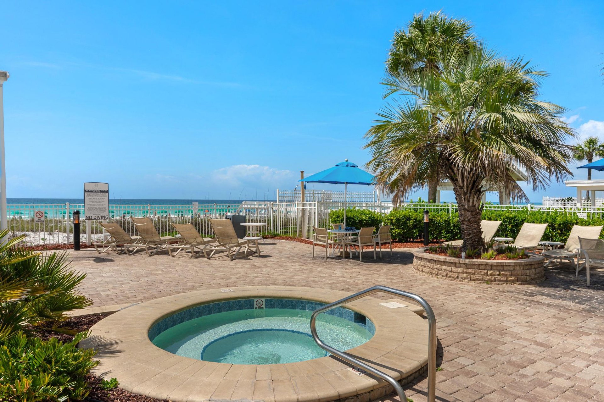 Tropical pool deck with hot tub and loungers leads to pristine beachfront paradise.