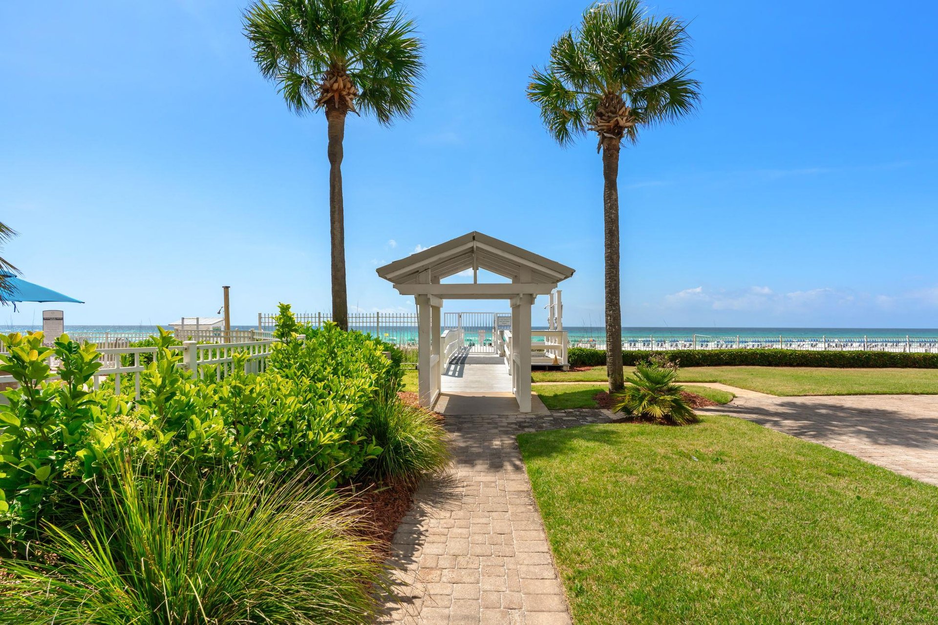 Beautiful beachfront property with tropical landscaping and covered pavilion leading to pristine sandy shores.
