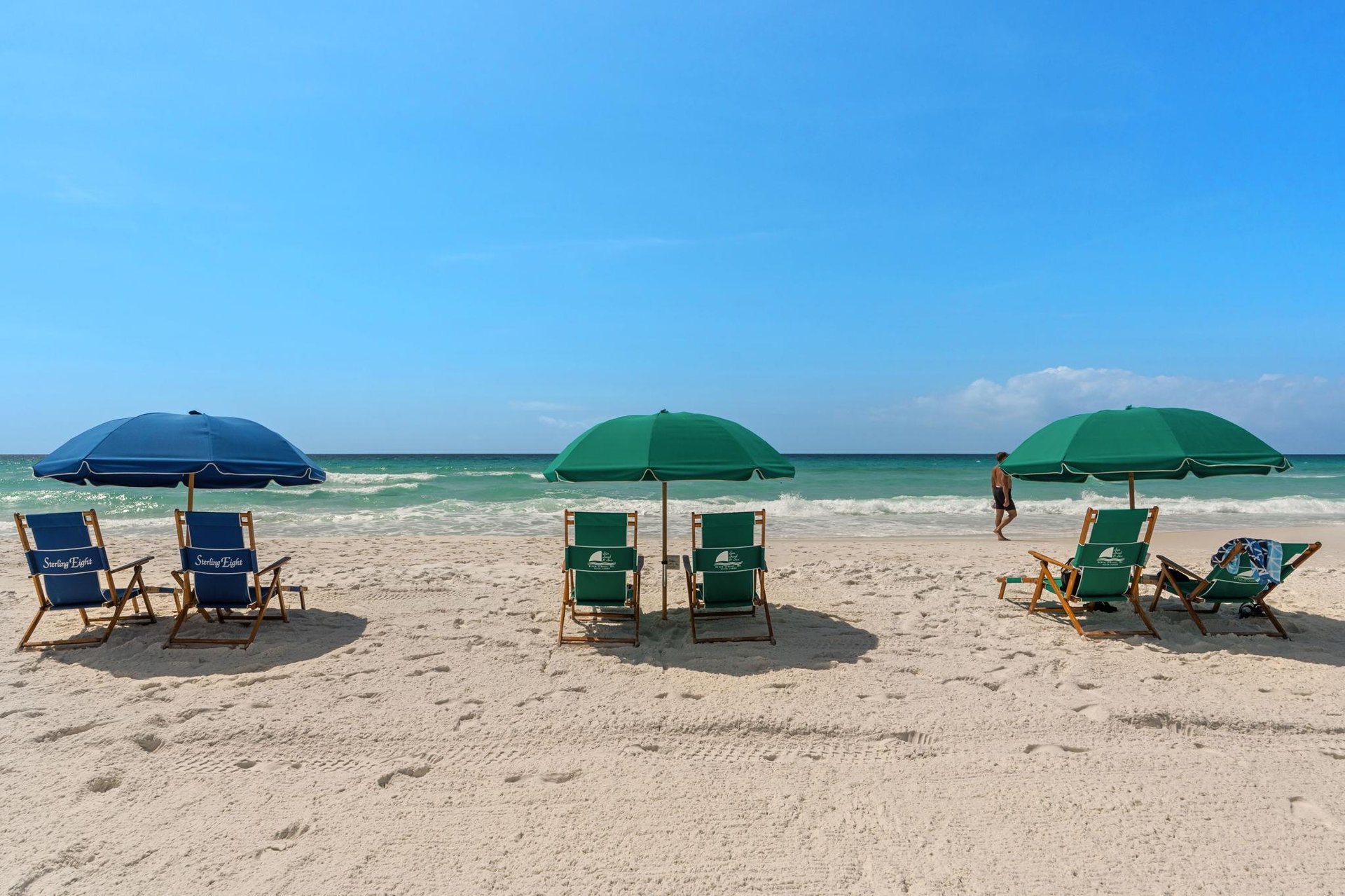 Beautiful white sand beach with colorful umbrellas and chairs set up along the pristine shoreline.