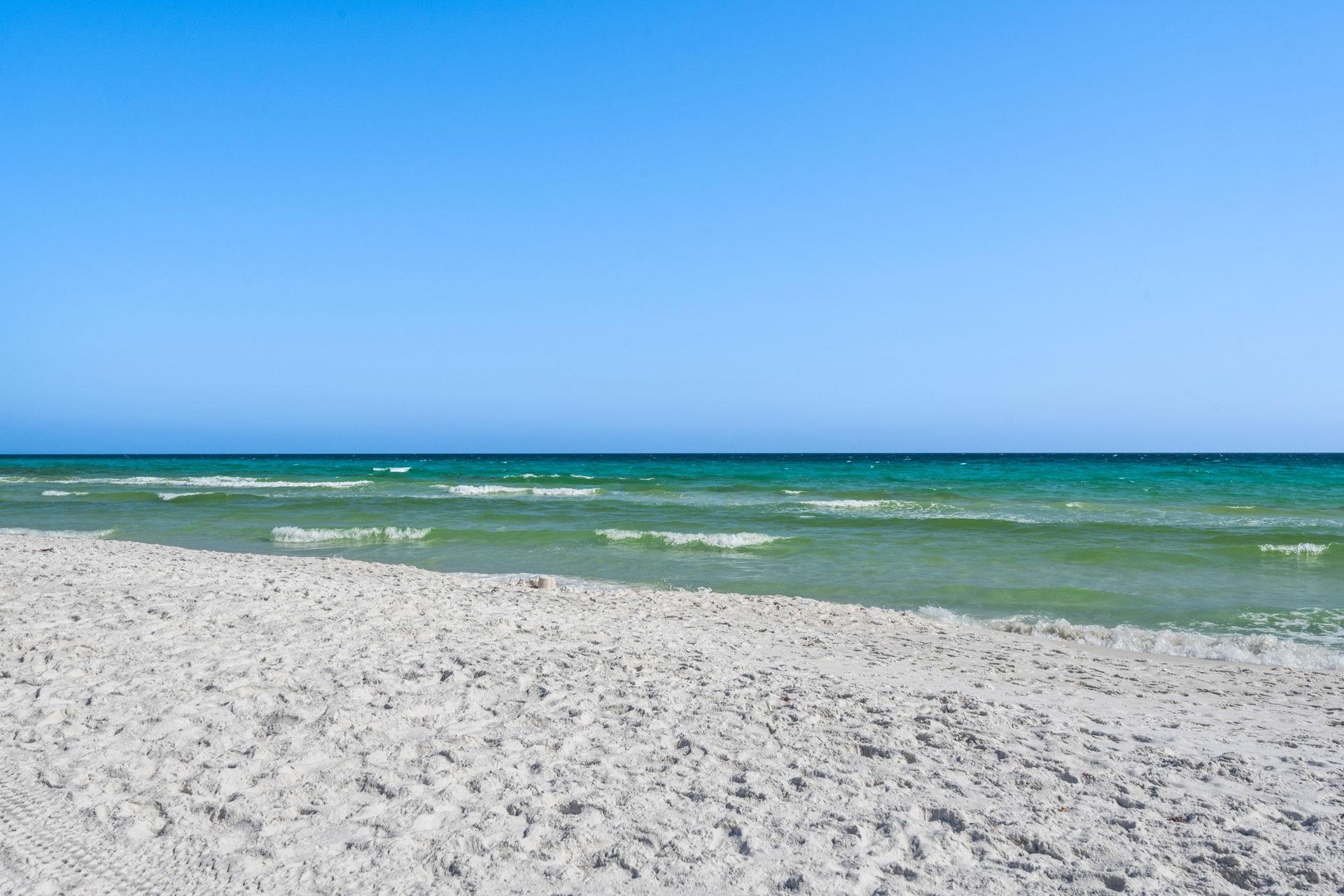 White sand beach with crystalclear turquoise waters and gentle waves under a bright blue sky