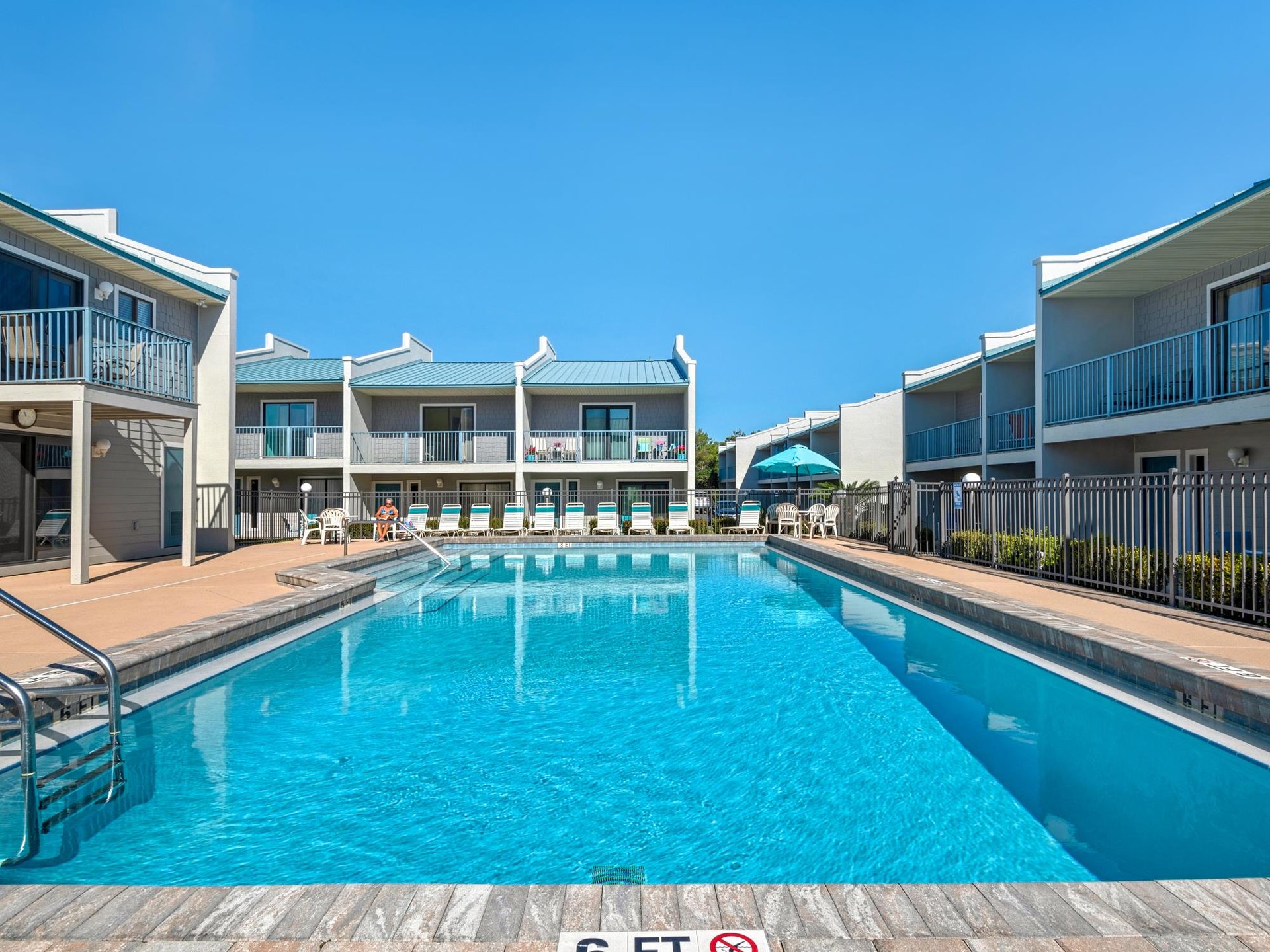 Crystalclear pool surrounded by comfortable accommodations under brilliant blue skies, creating the perfect backdrop for your relaxing getaway.