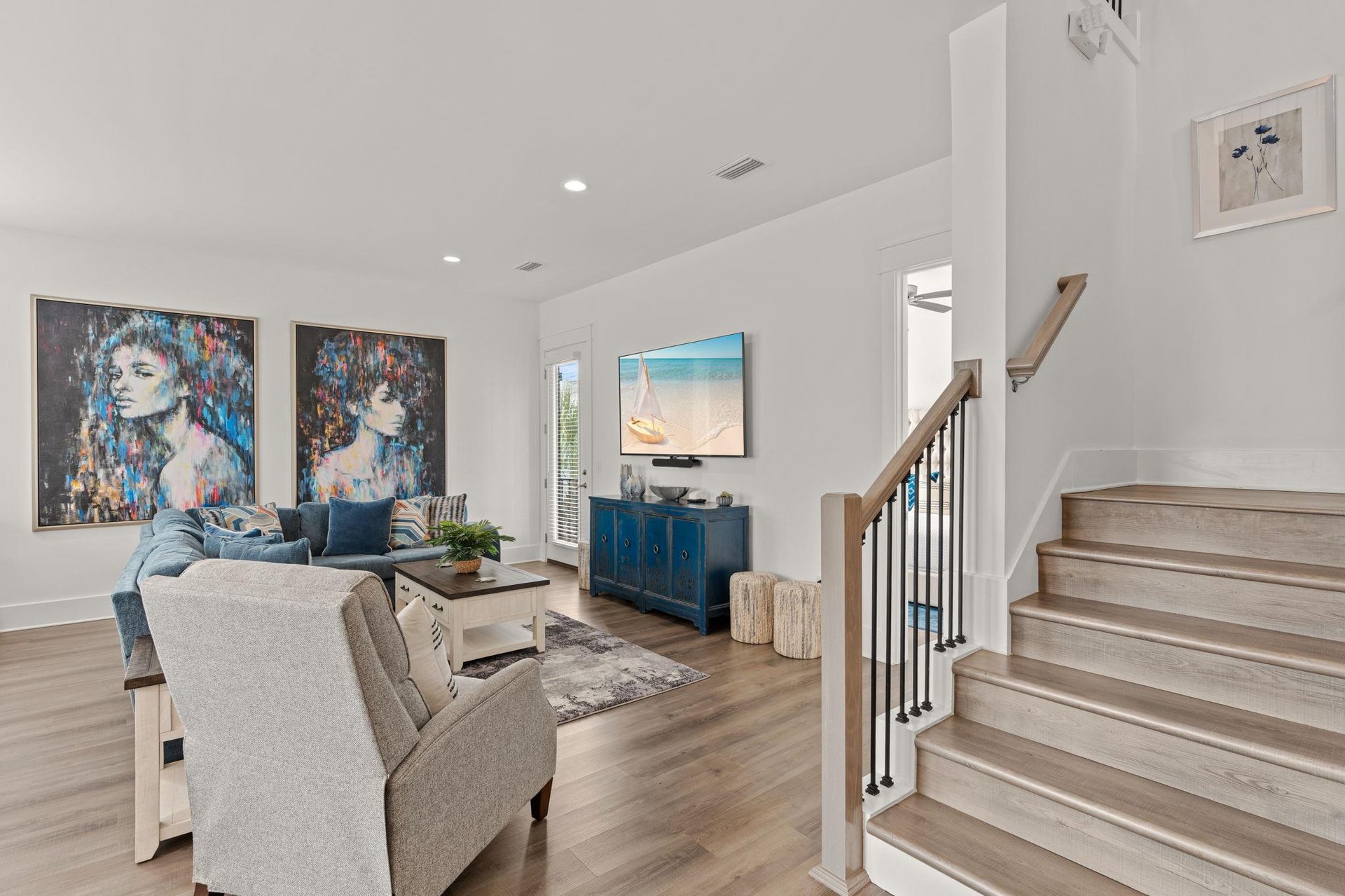 Settle into your bright, open living room with coastal art, cozy seating, and natural light—a perfect spot to unwind after exploring the area.