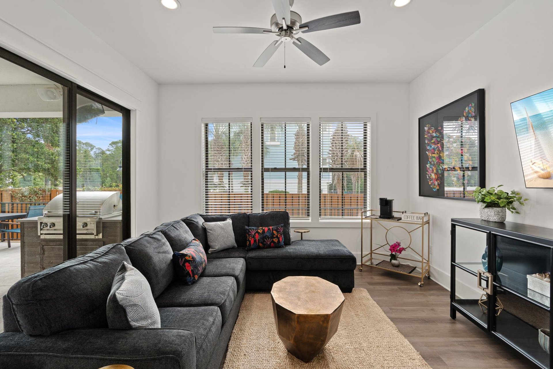 Sink into plush charcoal seating as the ceiling fan cools you. Natural light pours through sliding doors to your private patio with builtin grill—perfect for lazy mornings and evening gatherings.