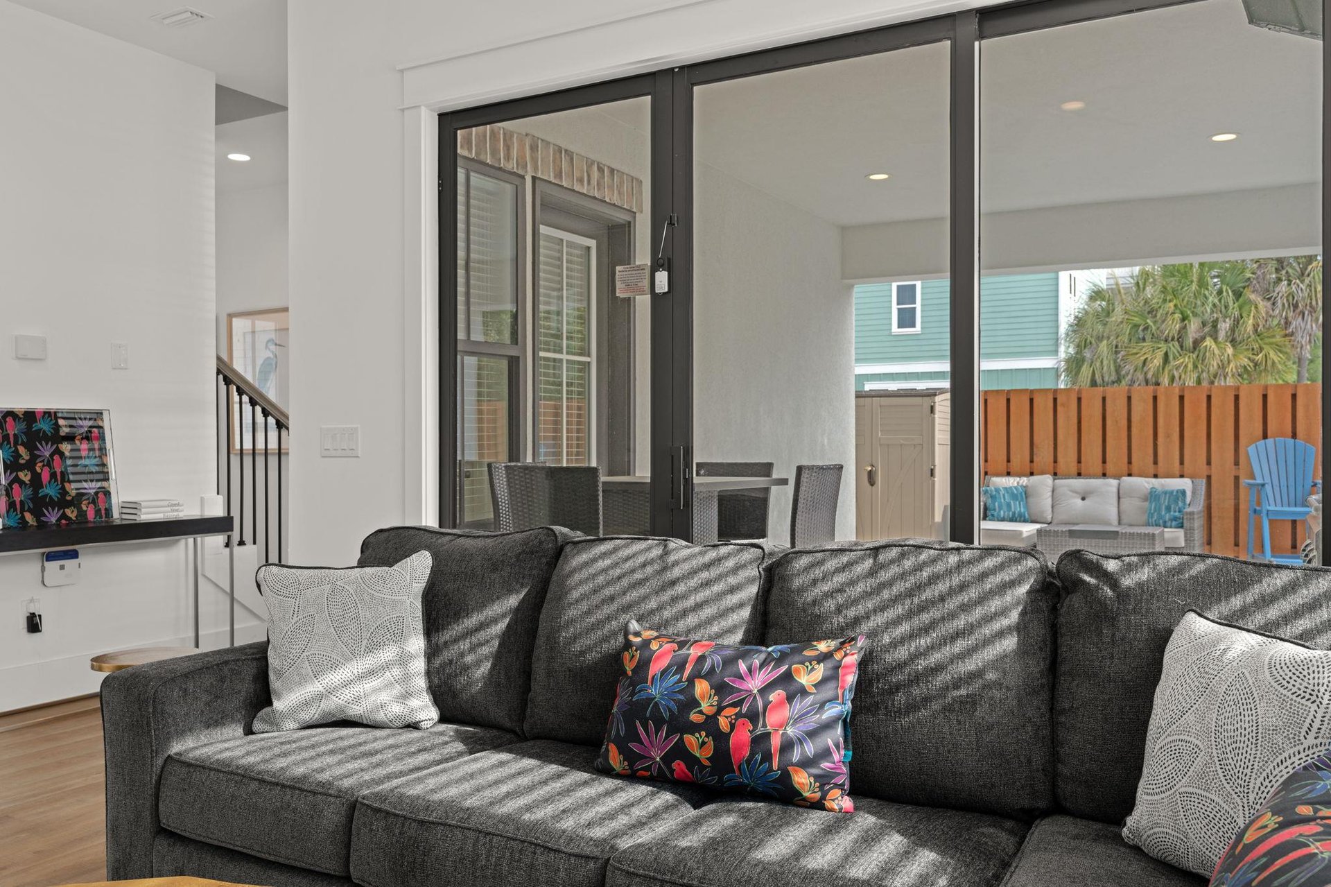 Sink into plush seating while natural light streams through expansive glass doors connecting your living space to a private patio  pool area complete with outdoor furniture and lush tropical greenery