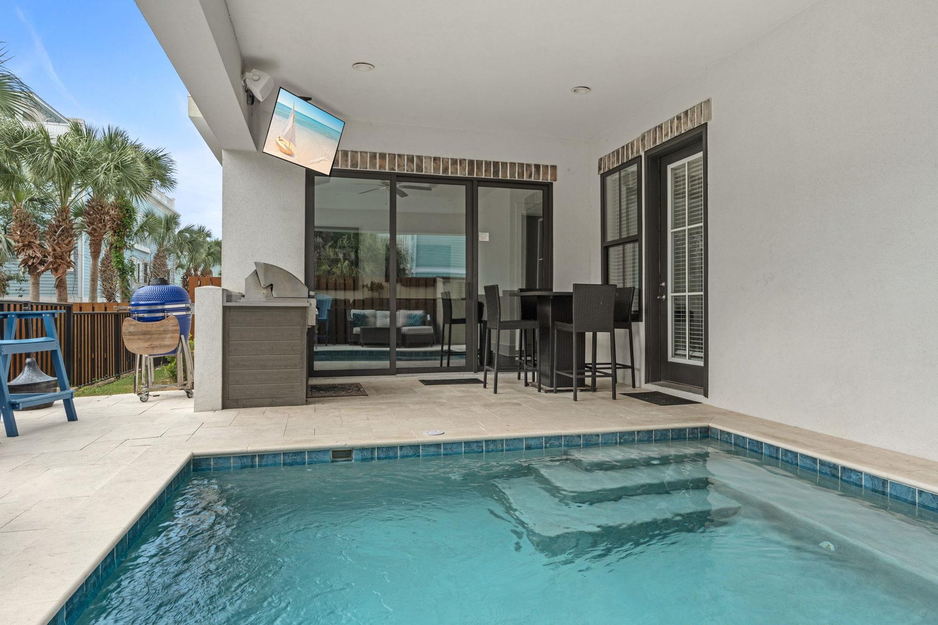Your private patio features a sparkling plunge pool, outdoor bar seating, builtin grill, and a TV for alfresco dining and relaxing under the palms.