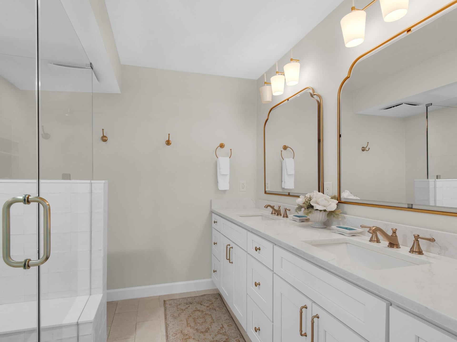 Your spainspired bathroom features dual sinks with elegant fixtures, soft lighting, and a spacious glassenclosed shower—perfect for refreshing after sunfilled days.