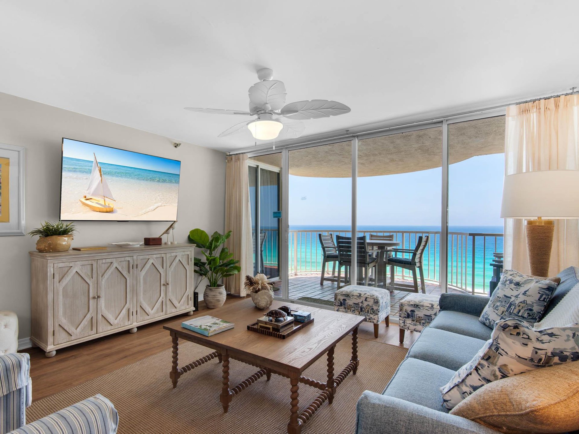 Step into your coastal living room where turquoise waters stretch endlessly beyond your private balcony. Sink into plush seating, feel the ceiling fans gentle breeze, and unwind as ocean views frame 