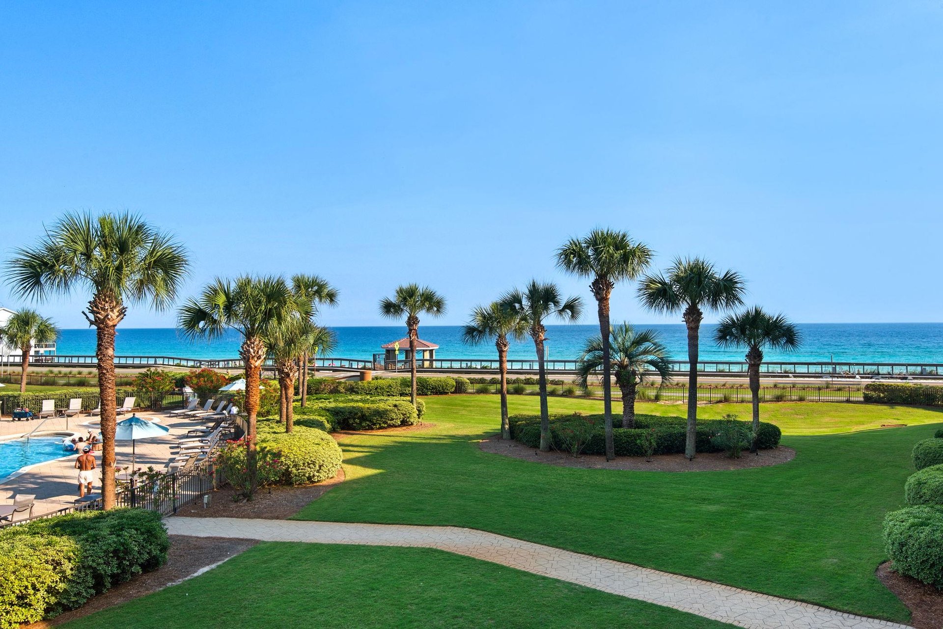 Beachfront resort property featuring manicured grounds with palm trees, pool area, and direct beach access along the Florida coastline.