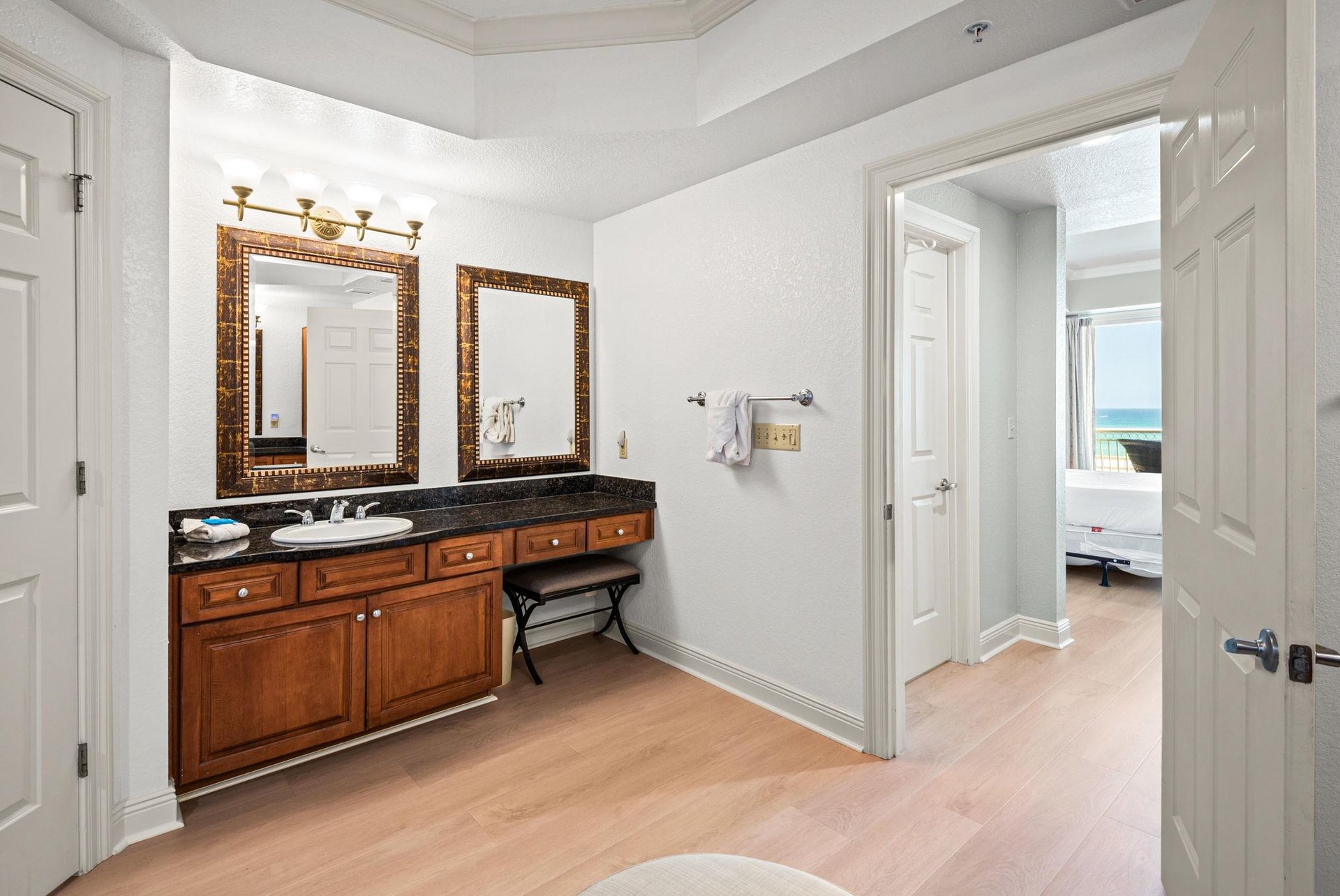 The Primary bathroom vanity features rich wood cabinetry, granite countertops, and elegant framed mirrors—perfect for refreshing each morning.