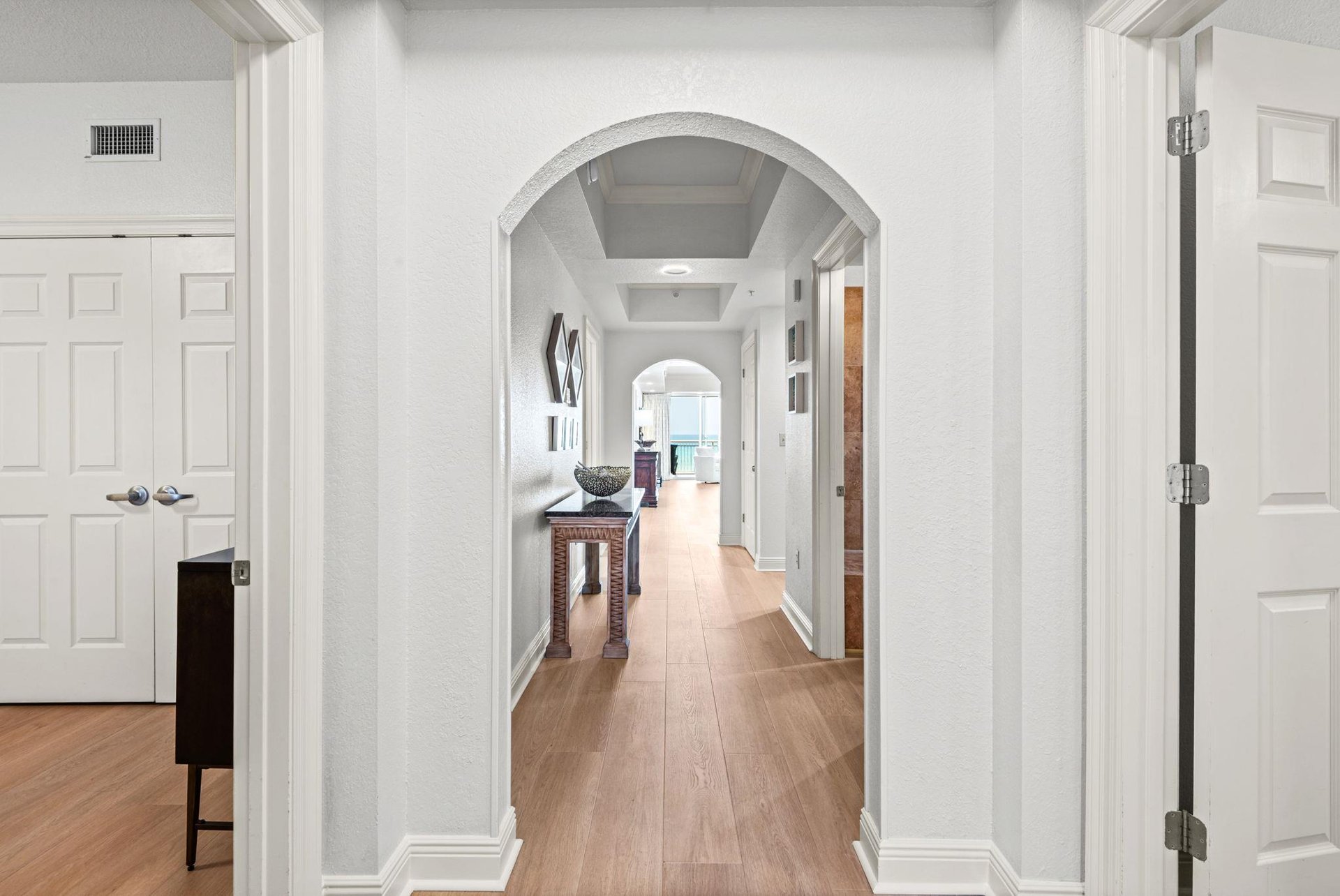 Elegant archways frame this bright hallway, leading you toward serene Gulf views and spaces for your comfort.