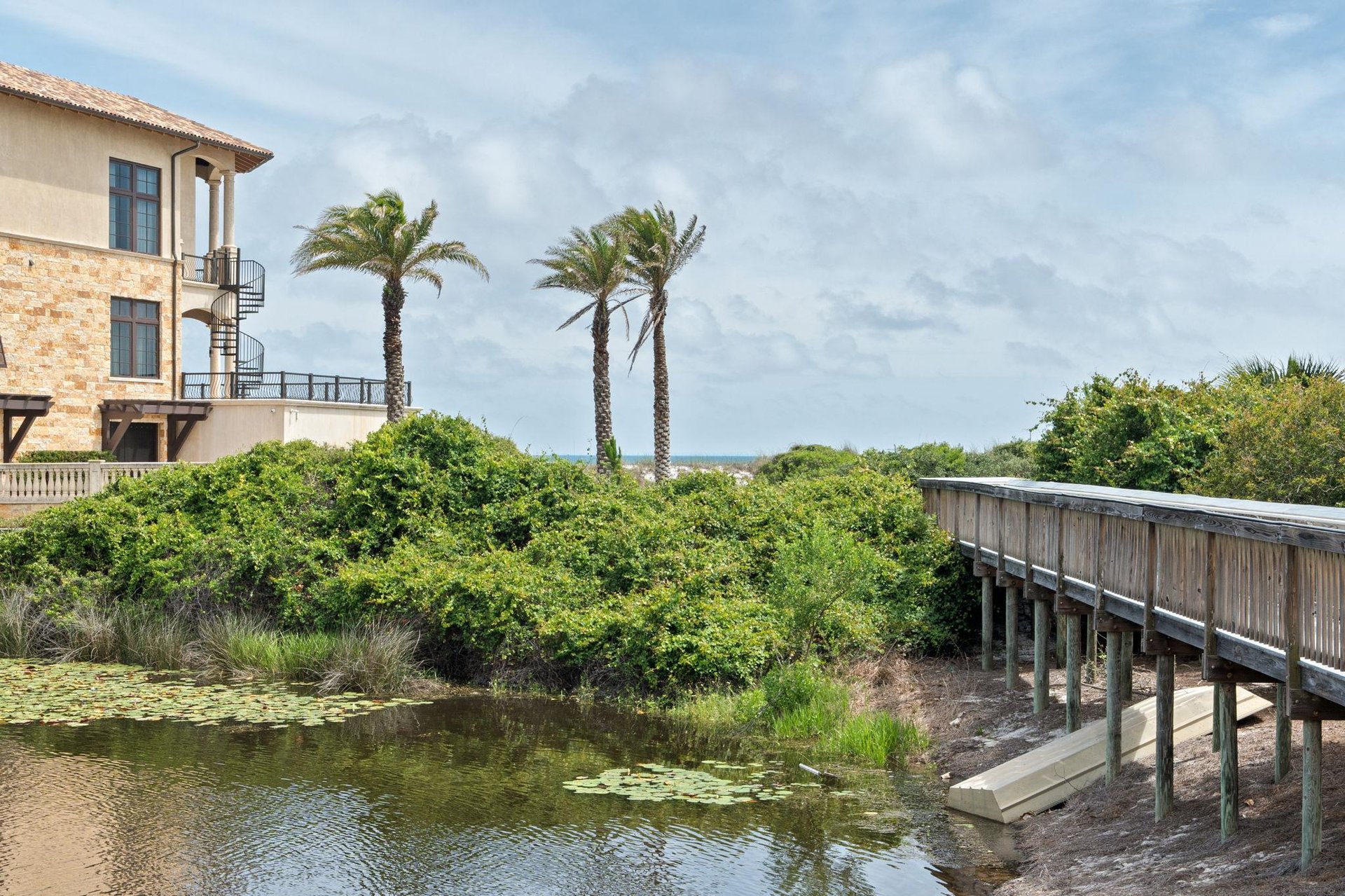 Waterfront property featuring palm trees, coastal views, and direct boardwalk access to nearby beaches and natural landscapes.
