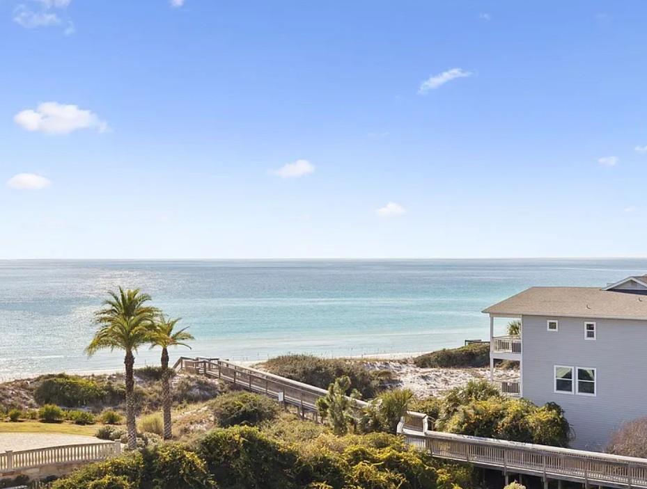 Coastal property featuring direct beach access via boardwalk, tropical landscaping, and stunning ocean views in a serene beachfront community.