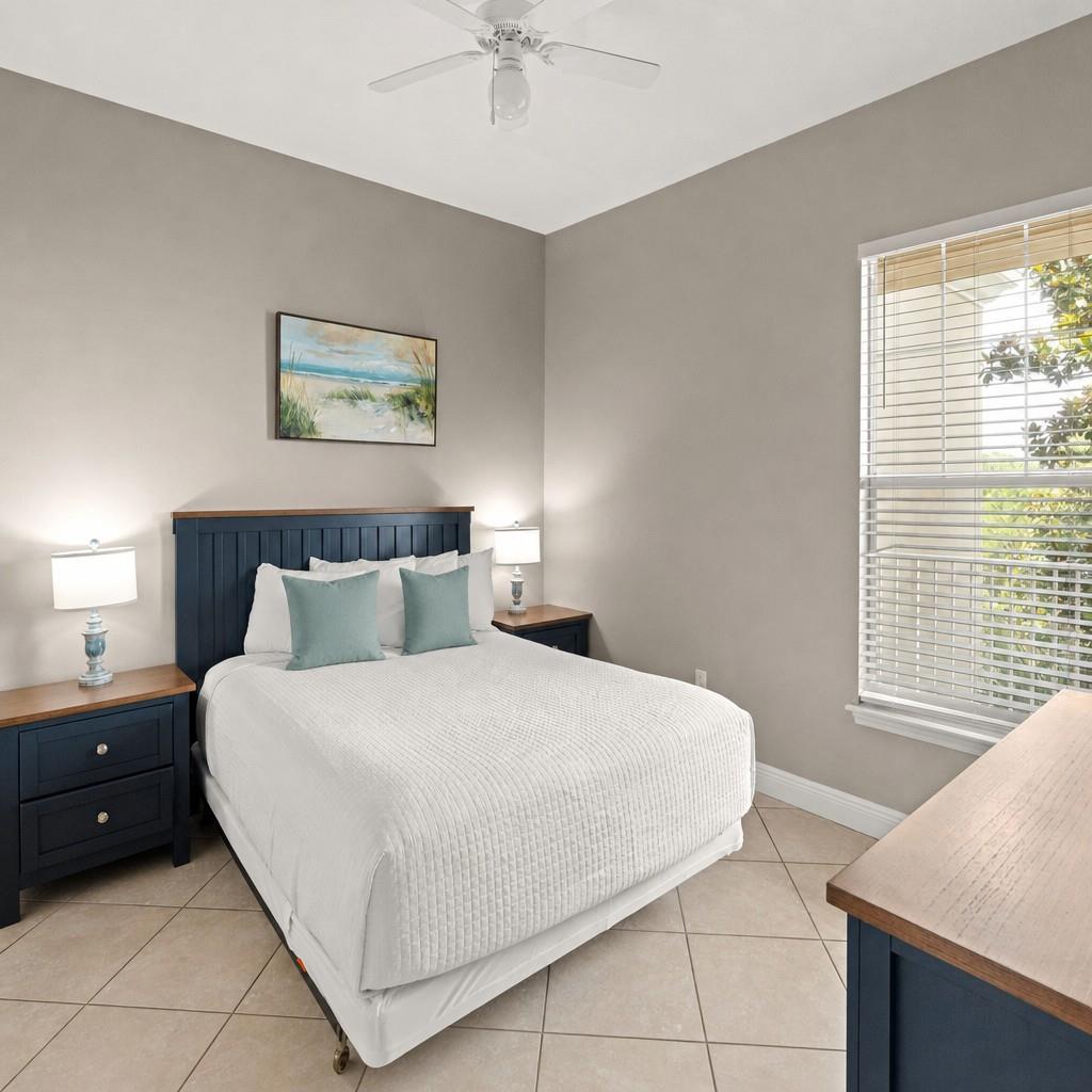 Guest bedroom features crisp linens and coastal charm, with natural light streaming through the window to brighten your peaceful retreat after a day of adventure.