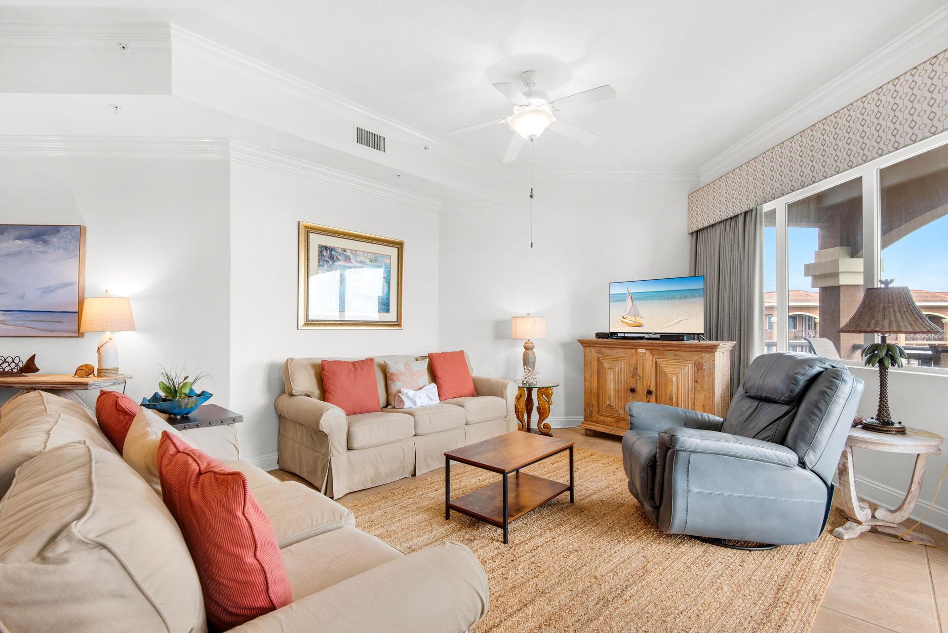 Unwind in your spacious living room with plush seating, coastal décor, and a ceiling fan to keep you cool.
