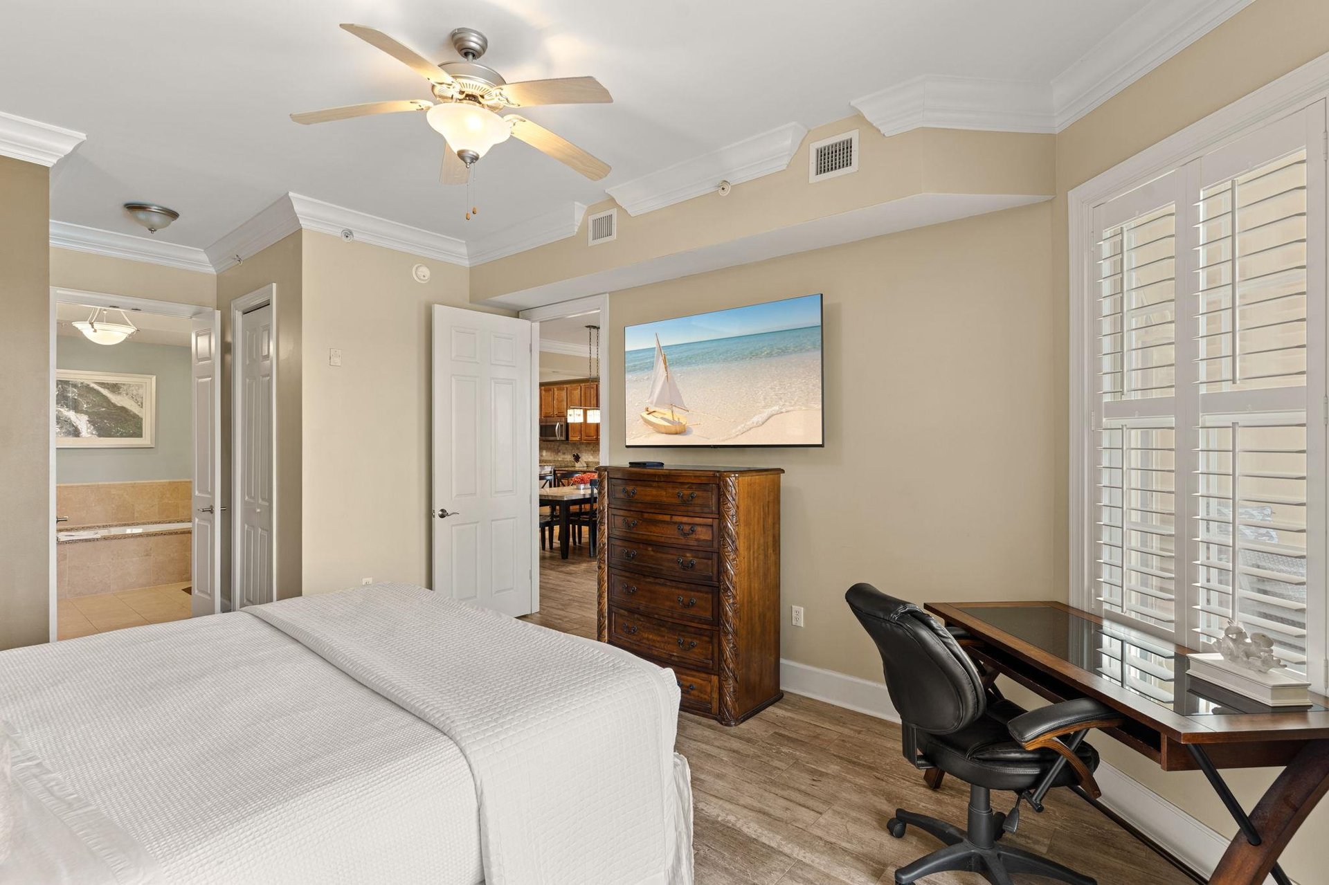Peaceful king bedroom retreat features a plush bed, ceiling fan for comfort, and elegant coastal artwork that sets the tone for your relaxing getaway.