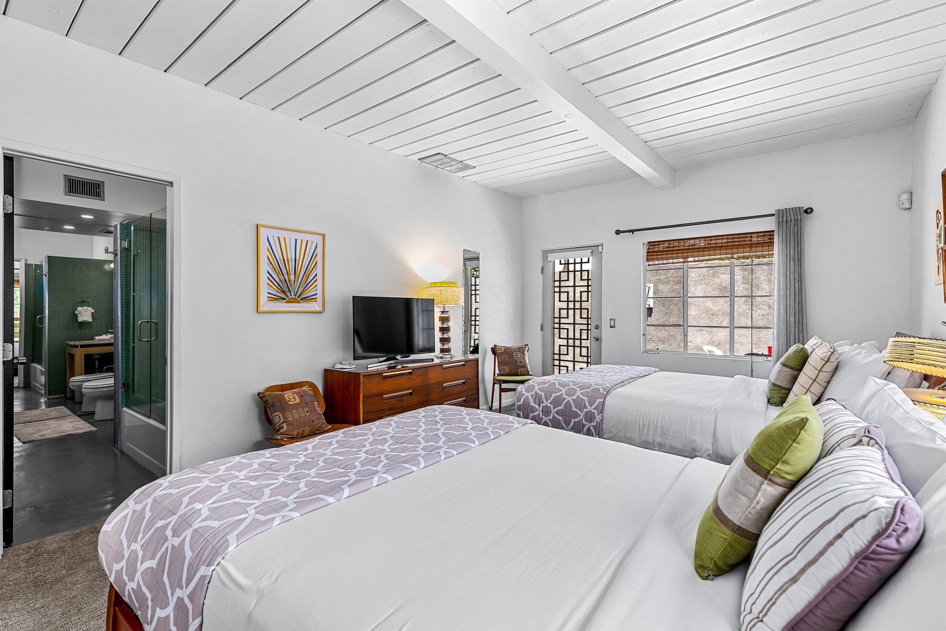 View of TV on dresser and private patio door from queen bed