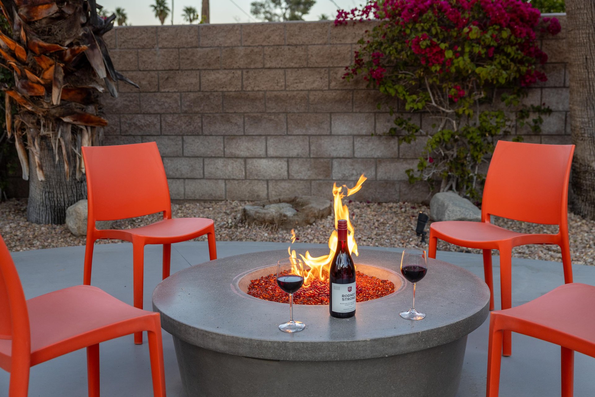 Firepit surrounded by four orange chairs