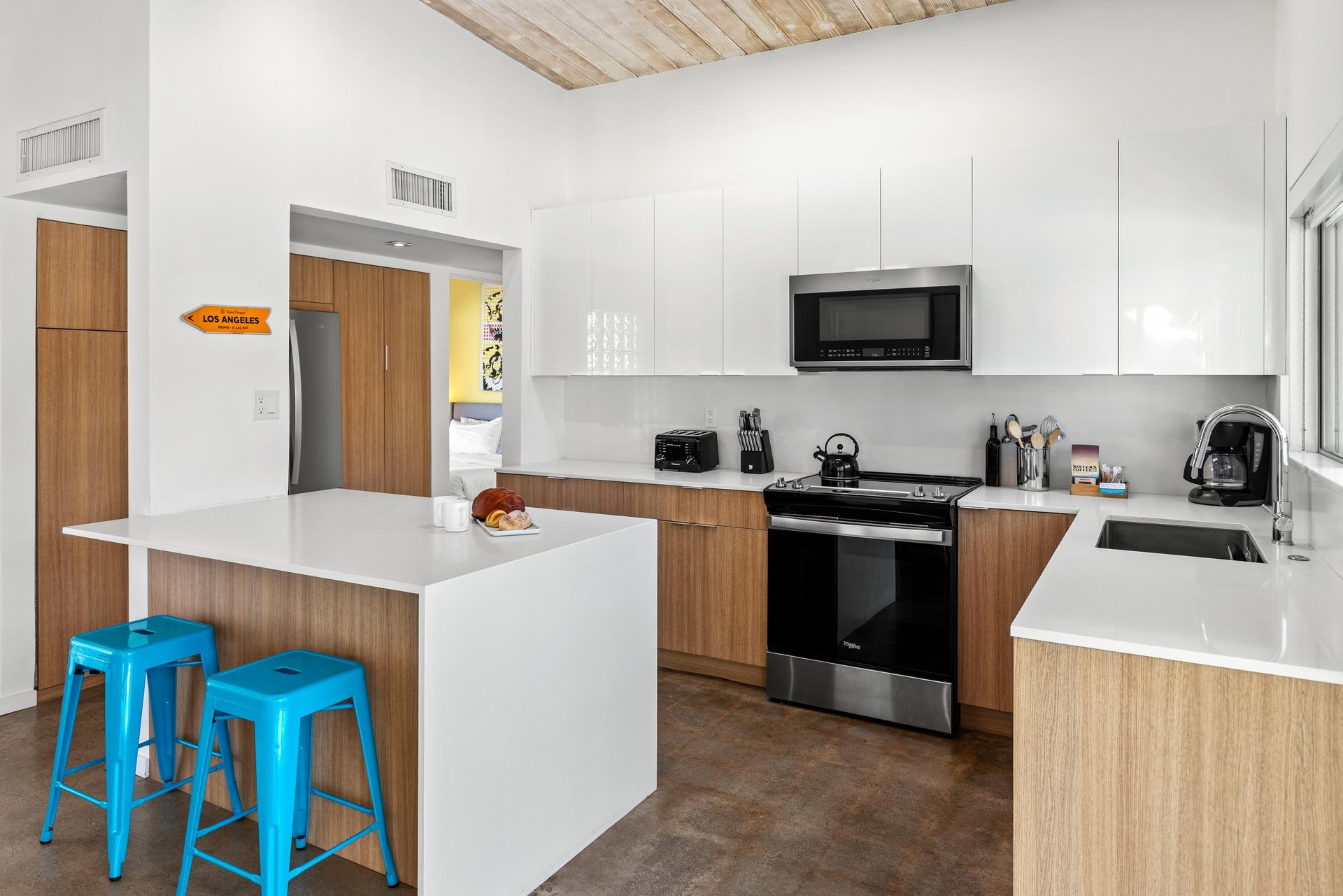 Your modern kitchen features sleek white countertops, woodgrain cabinets, and stainless steel appliances perfect for preparing meals during your stay.