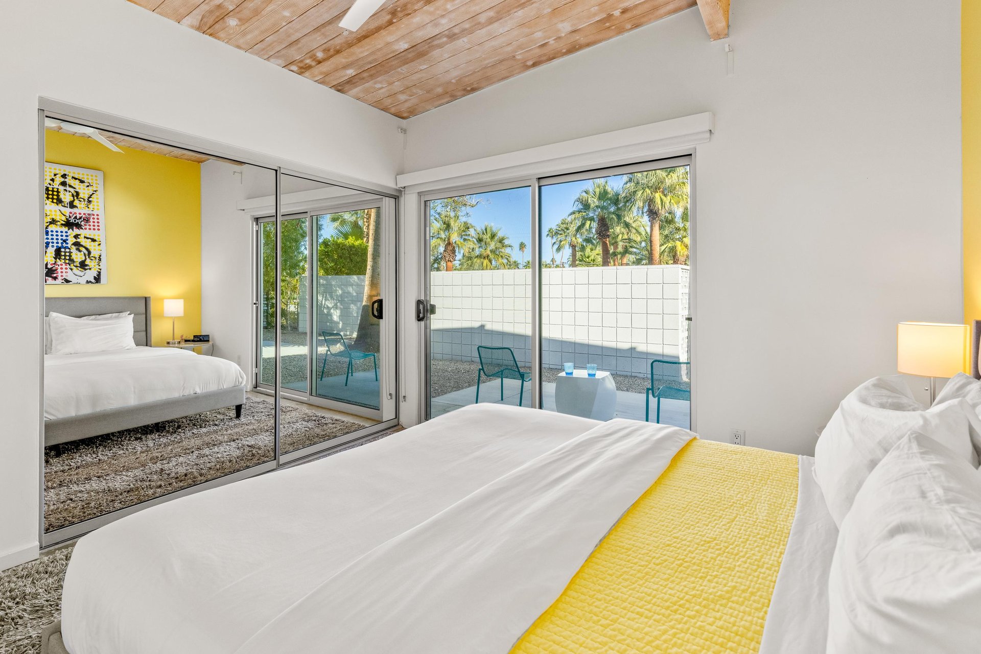 Wake up to sunshine streaming through floortoceiling windows in your midcentury bedroom, where warm wood ceilings and bright yellow accents create cheerful mornings.