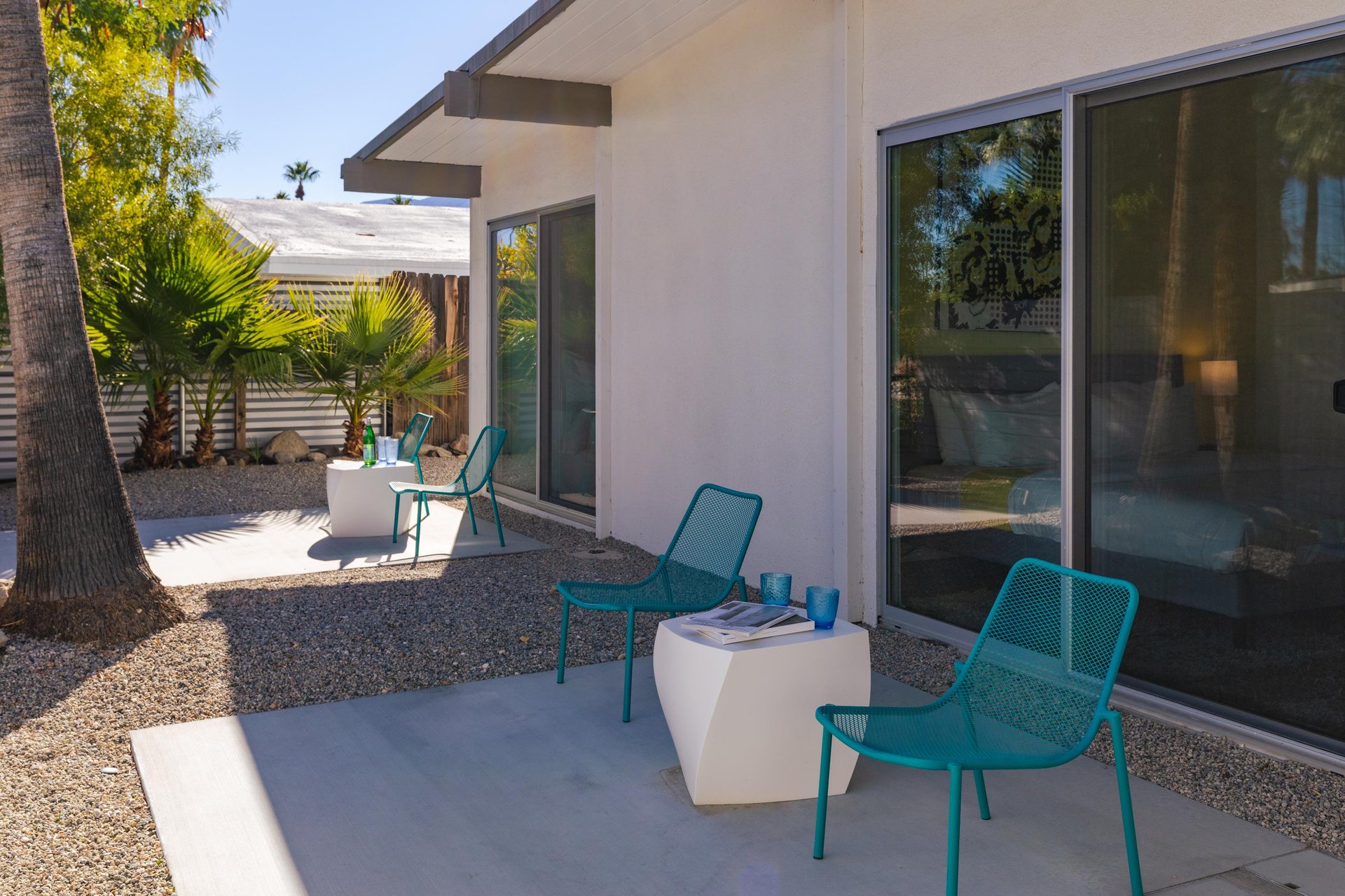 Unwind on your private patio with modern teal seating and tropical palms, perfect for morning coffee or evening relaxation.
