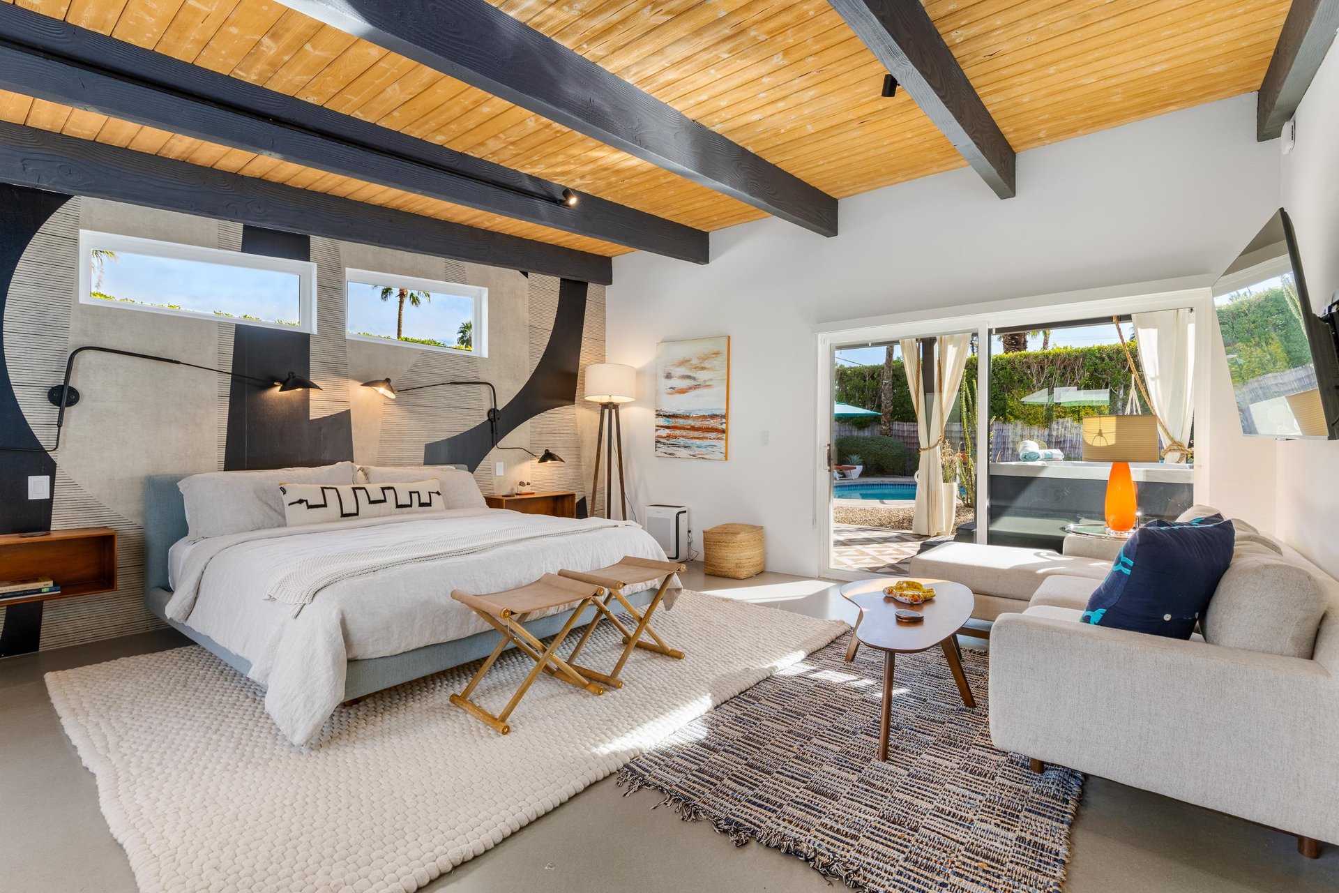Relax in this stunning suite where rustic beams meet modern comfort, featuring direct pool access and stylish furnishings.