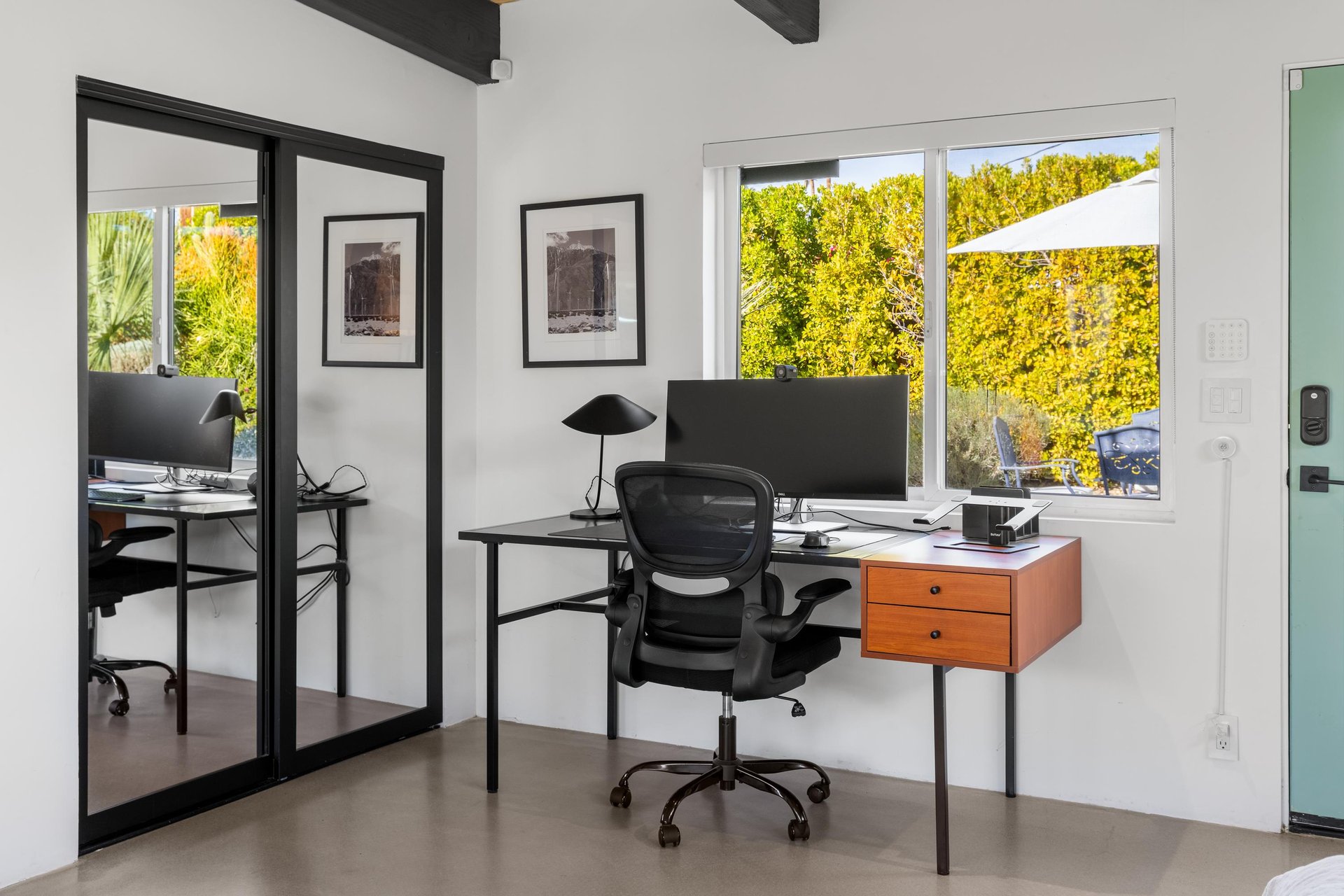 Your dedicated workspace with modern desk, ergonomic chair, and dual monitors overlooks lush greenery through large windows.
