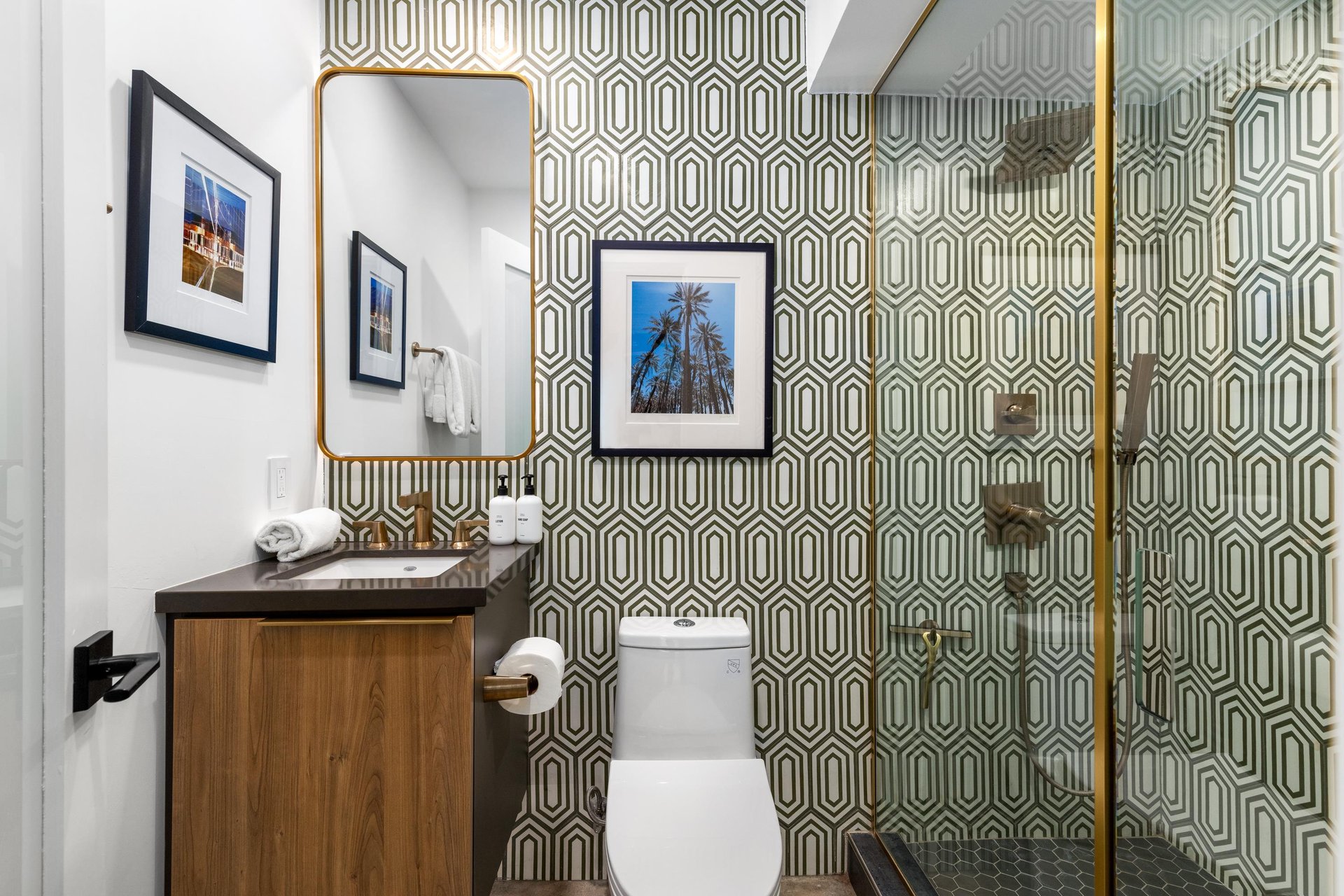 Step into your stylishly designed bathroom featuring geometric wallpaper, elegant brass fixtures, and thoughtful artwork creating a sophisticated powder room experience.